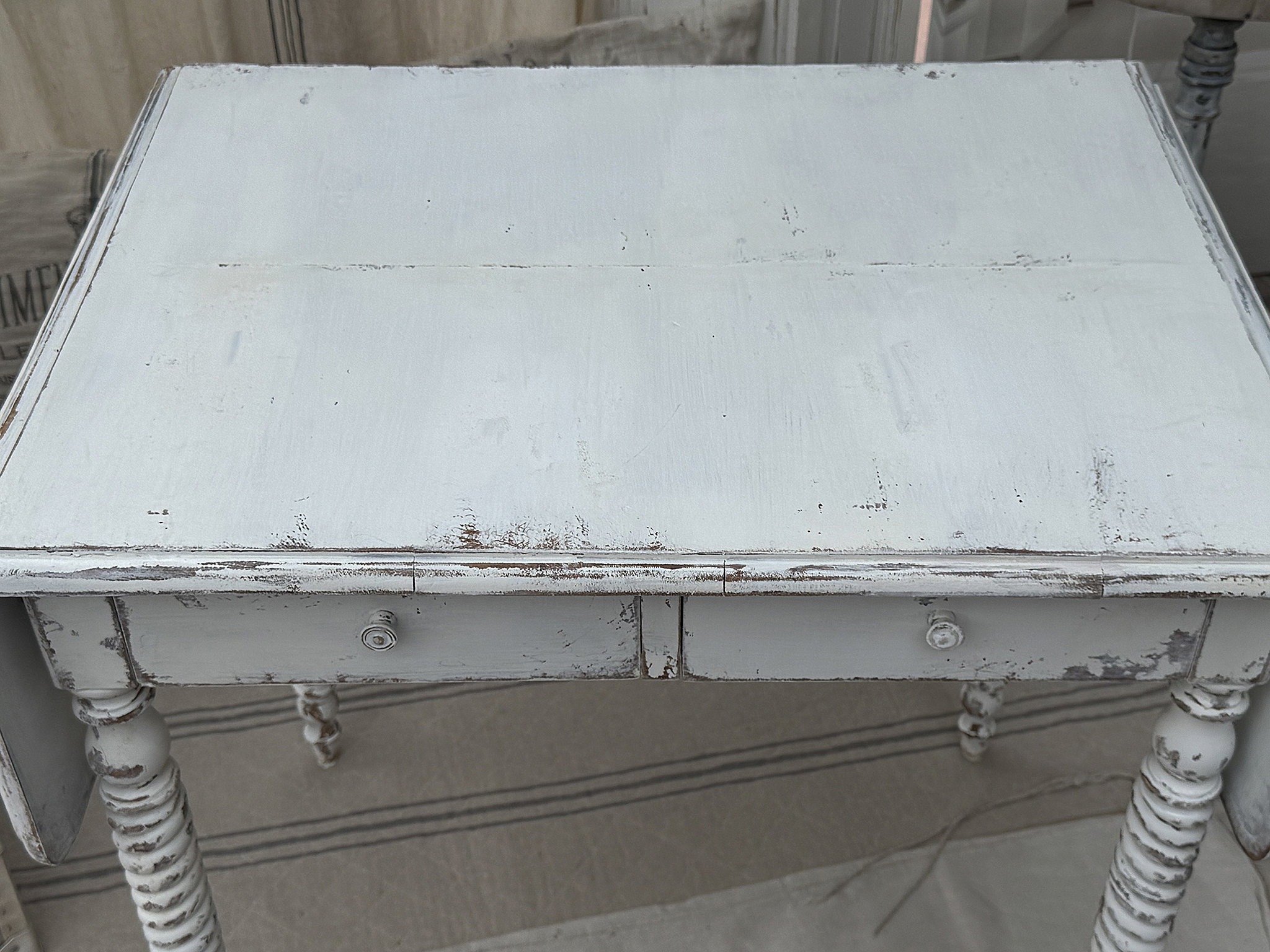 Obenansicht eines vintage Tisches im shabby-chic Stil mit zwei Schubladen und abgenutzter, weißer Farbe.