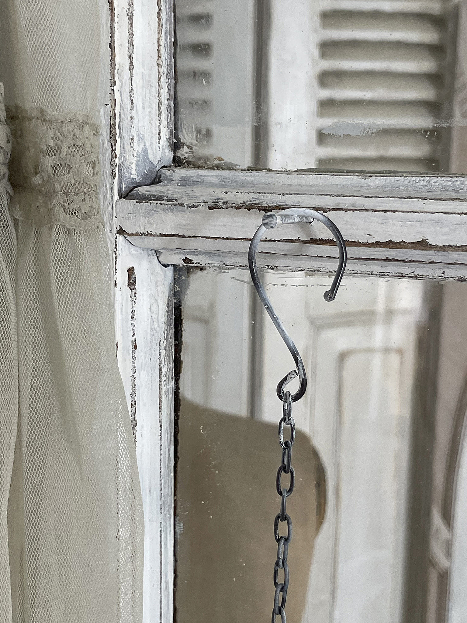 Ein Fensterhaken mit Kette und transparenter Gardine in einem Raum