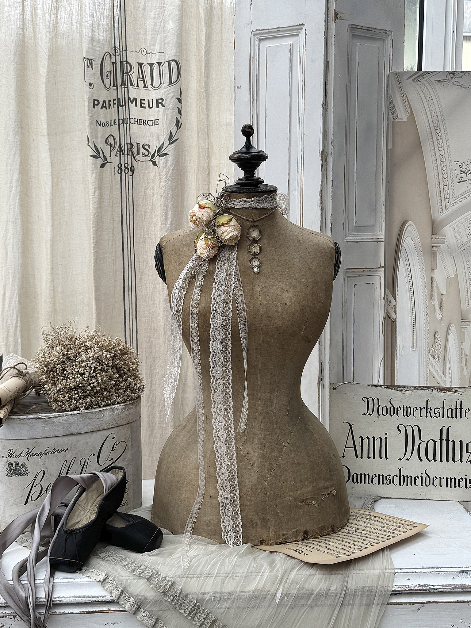 Antiker Schneiderpuppen-Ständer mit Dekoration und Materialien Antike Schneiderpuppe mit Spitze, Blumen und Ballettschuhen auf einem Tisch