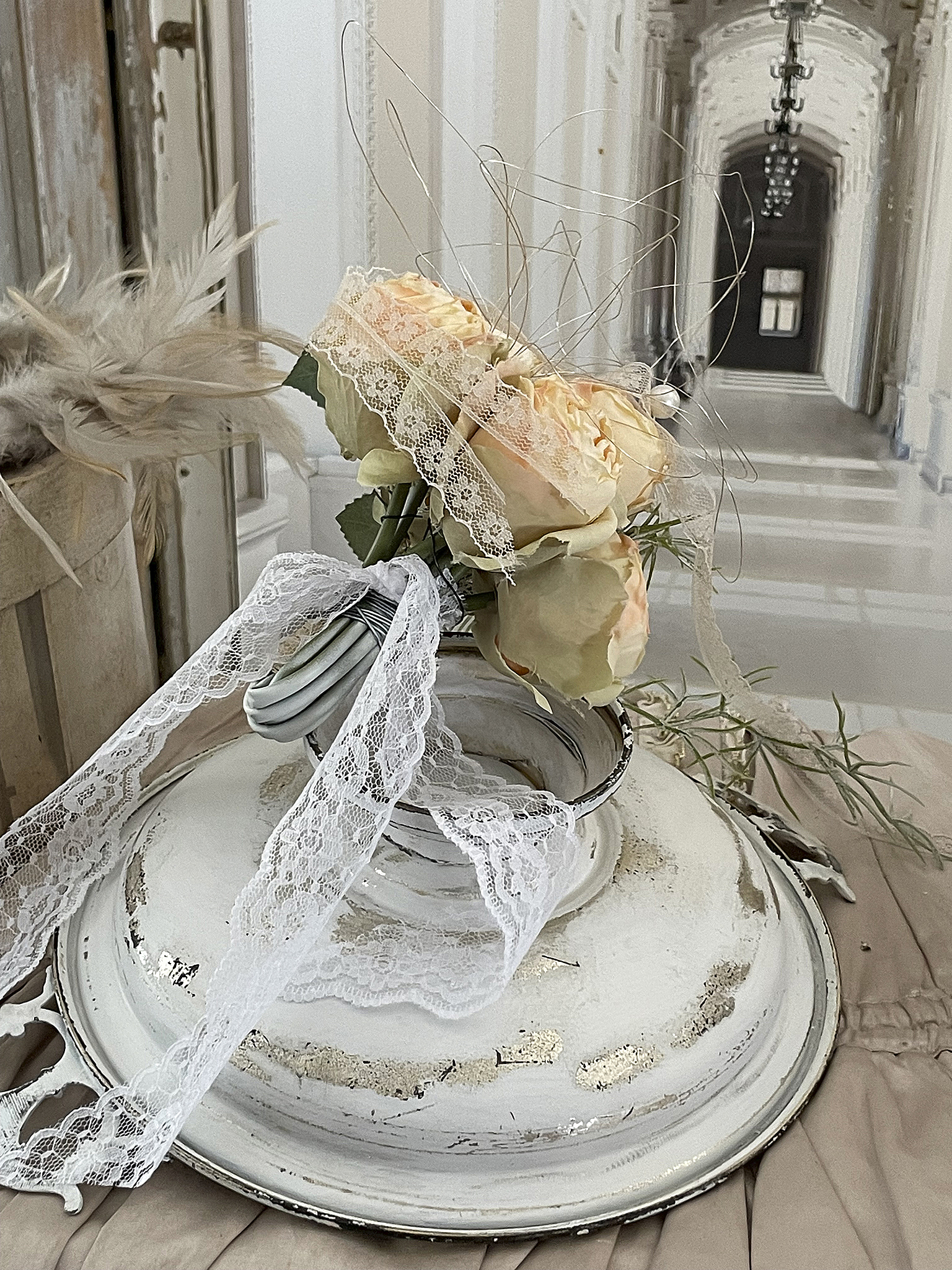 Blumenarrangement mit Rosen und Spitze auf einer antiken Schale