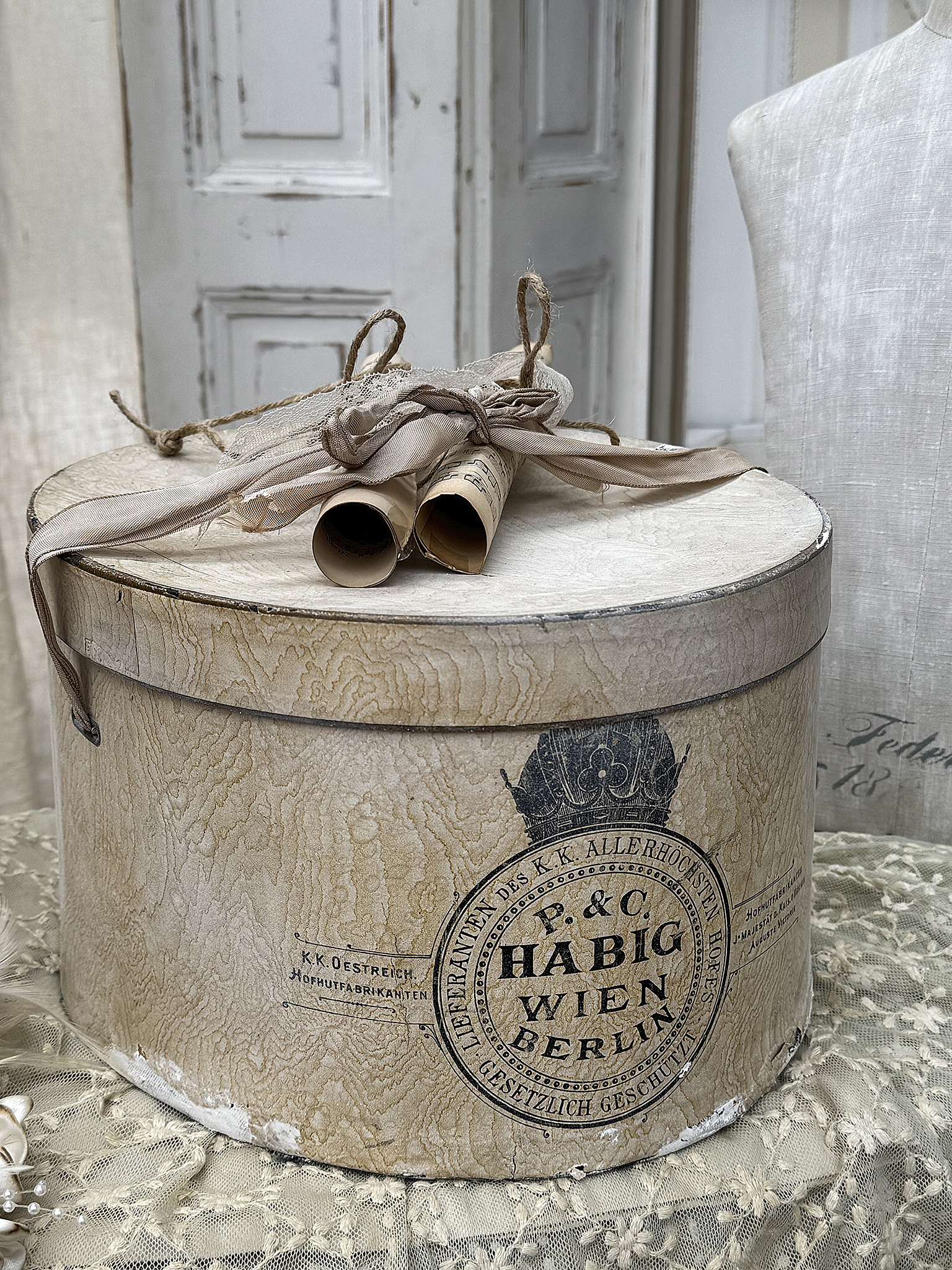 Vintage Rundbox mit alten Rollen und Schleife Deko mit alter Runde Box, Katalogrollen und Stoffschleife auf einem Tisch
