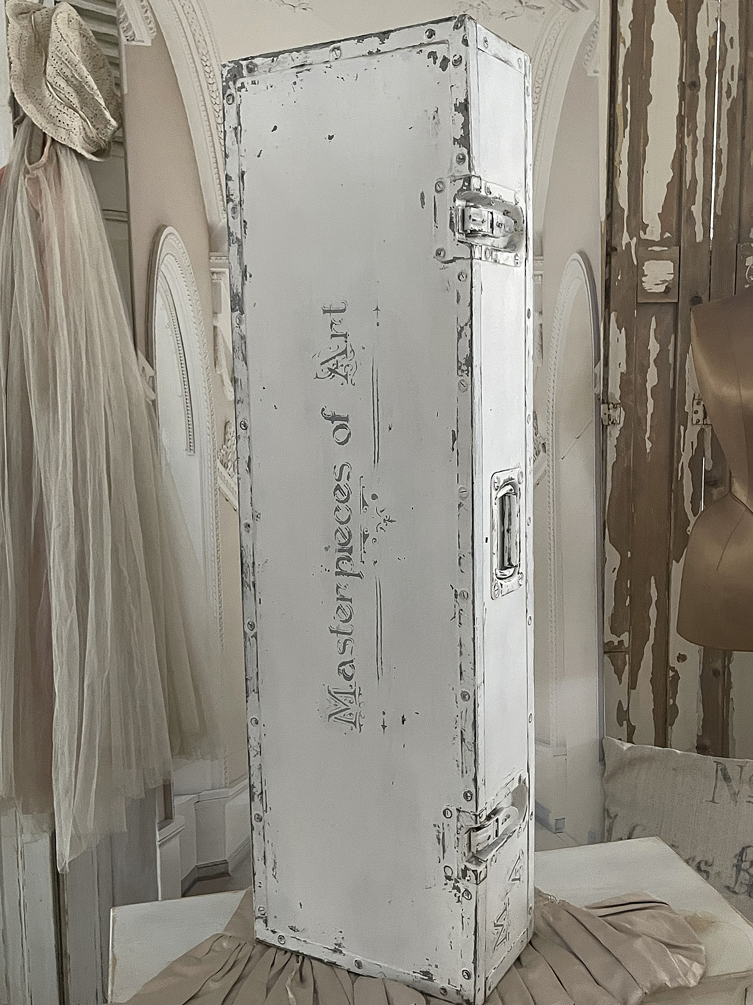 Antiker weißer Koffer mit beschädigtem Farbfinish und der Aufschrift 'Masterpieces of Art'.