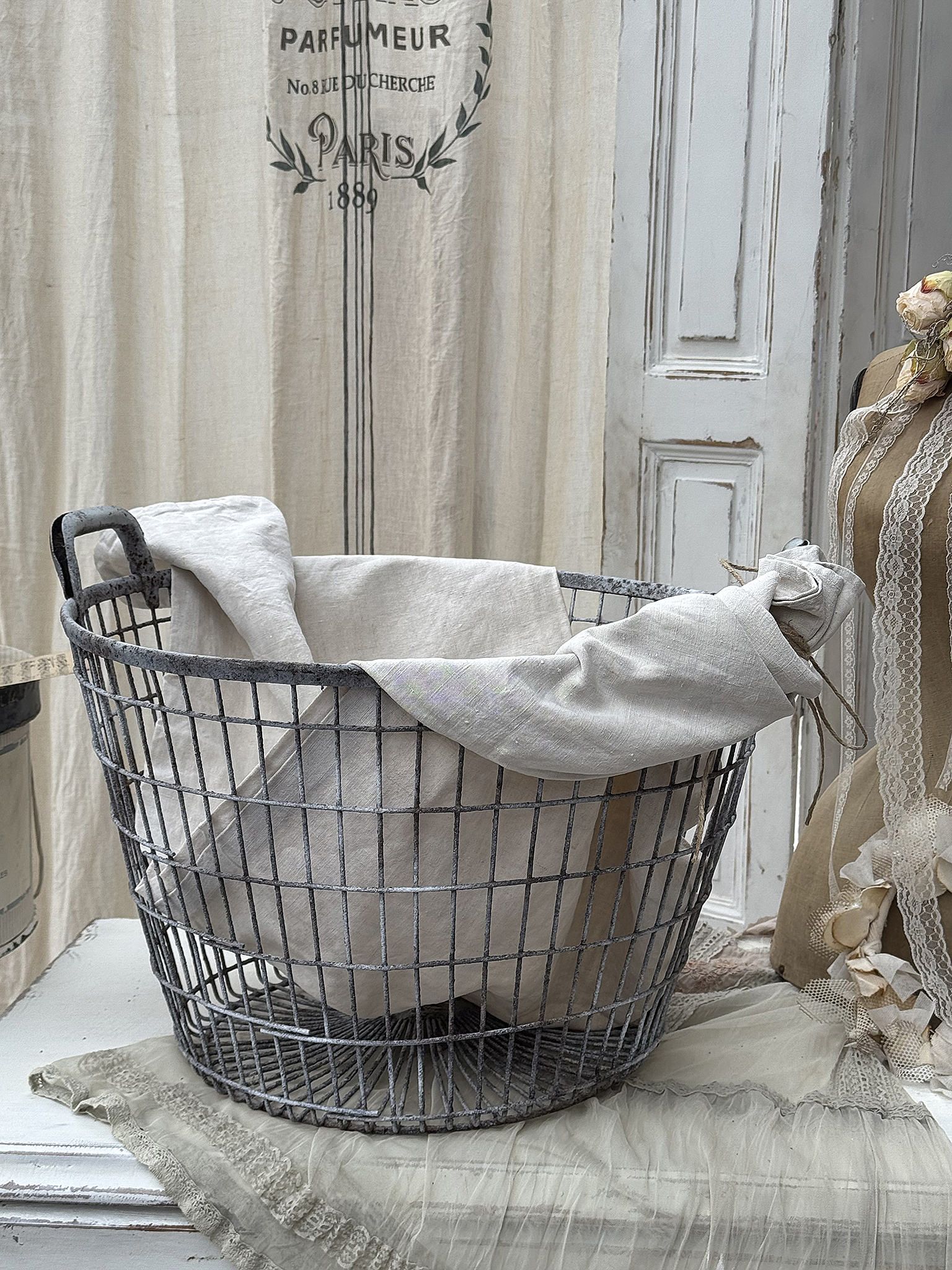 Vintage Wäschekorb aus Draht mit Leinen Drahtkorb für Wäsche, gefüllt mit hellen Leinentüchern, in schickem Vintage-Design