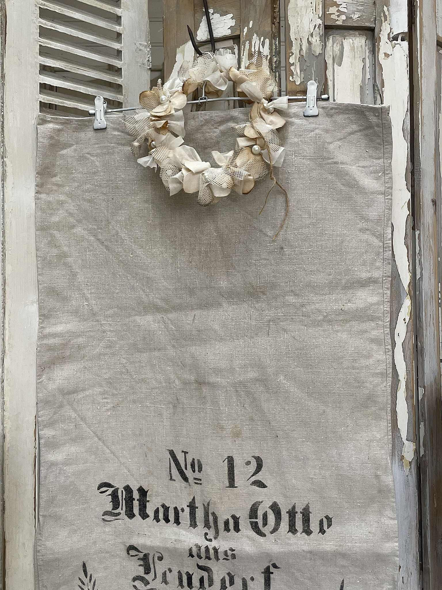 Stofftasche mit der Aufschrift 'Nr. 12 Martha Otto aus Penderft' und einem Kranz aus dekorativen Stoffblüten.