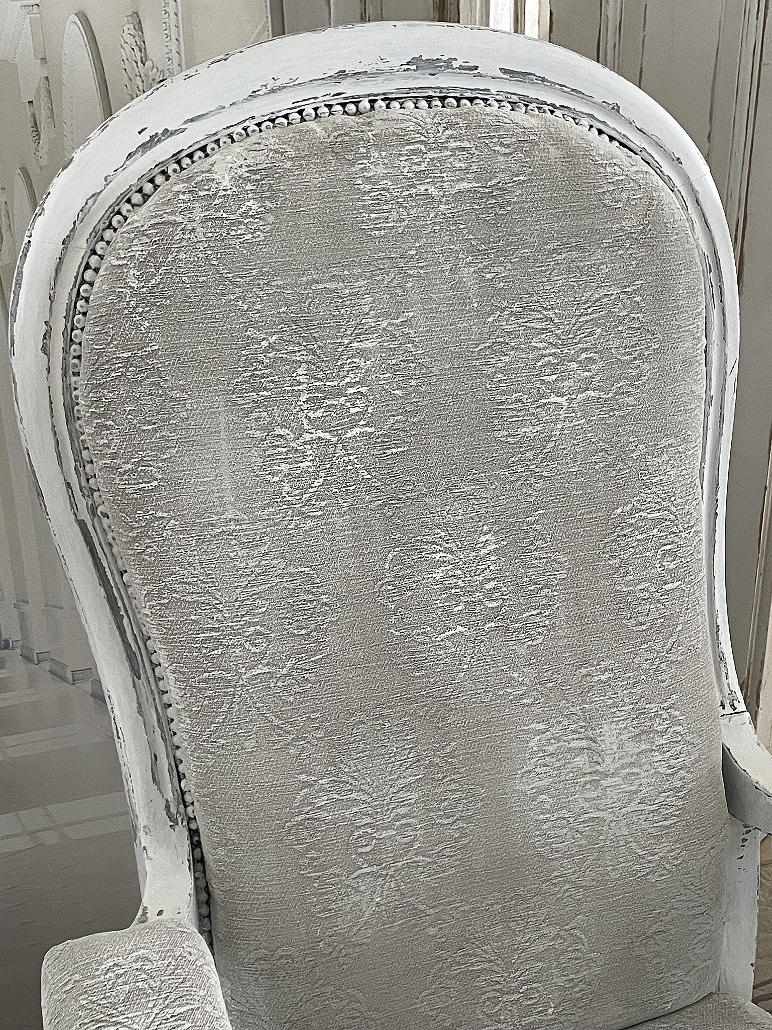 Nahaufnahme eines grauen, elegant gepolsterten Stuhls mit floralen Mustern und vintage-mäßigem Design