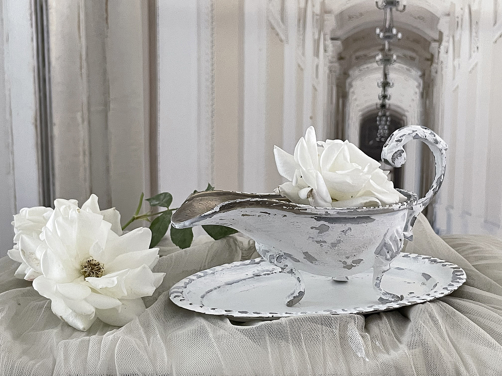 Antikes Geschirr mit weißen Rosen auf einem Tuch in einem hellen Ambiente