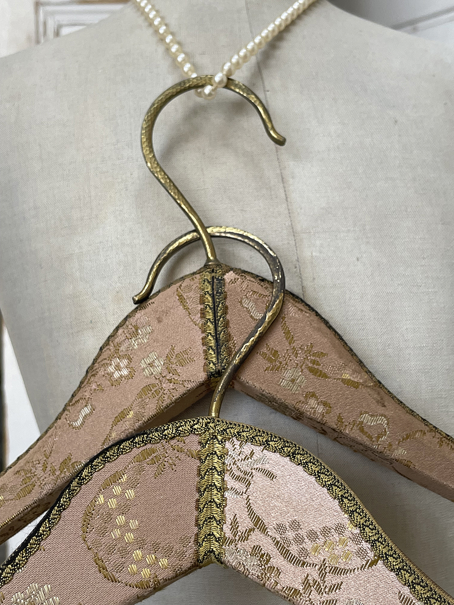 Elegante Kleiderbügel mit feiner Verzierung Zwei dekorative Kleiderbügel auf einer Schneiderpuppe, verziert mit goldenen und rosafarbenen Elementen.