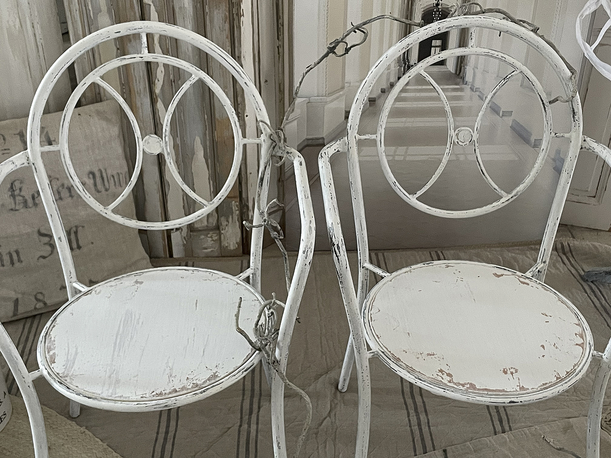 Zwei vintage weiße Stühle mit abgenutztem Look Zwei alte weiße Stühle mit abgeschliffenem Finish in einem Raum