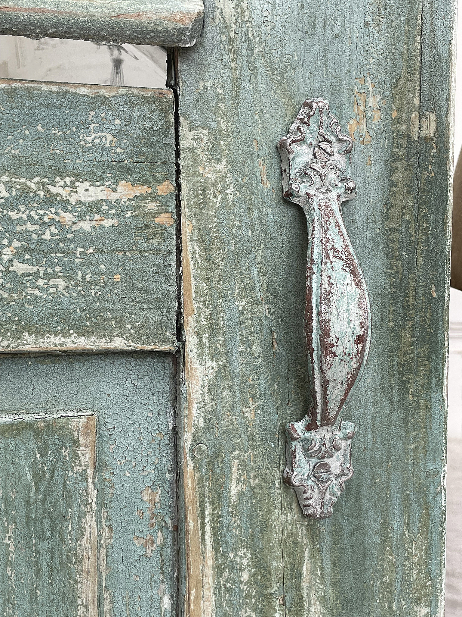 Antike Tür mit detailreichem Griff in Vintage-Optik Detailansicht einer antiken Tür mit grünem, abblätterndem Anstrich und kunstvollem Griff