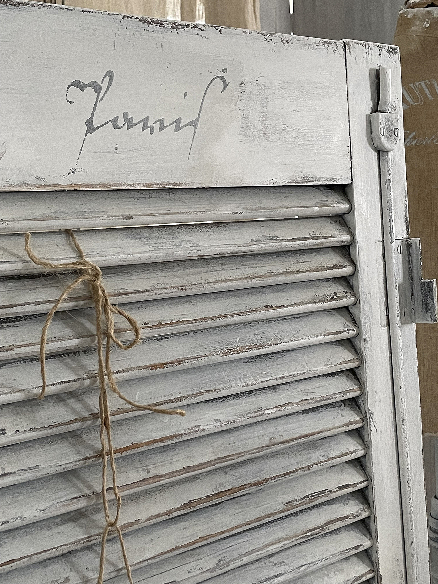 Dekorative weiße Fensterläden mit antikem Charme Detailaufnahme von antiken weißen Fensterläden mit handgemalter Signatur und Schnur