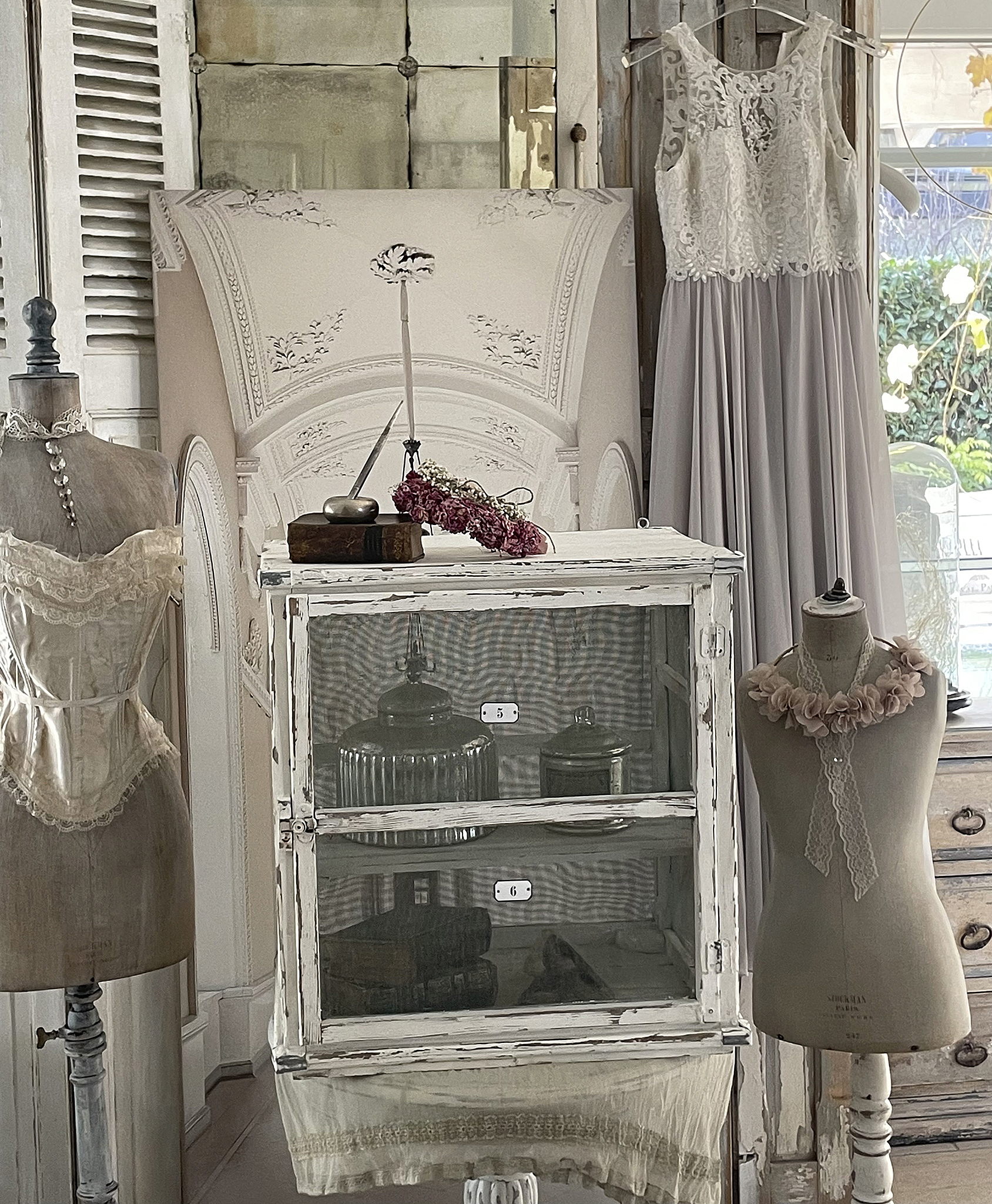 Antiker Vitrinenschrank mit nostalgischem Design und eleganter Mode Ansicht eines antiken Vitrinenschranks mit Vintage-Kleidern und Dekoration im Hintergrund