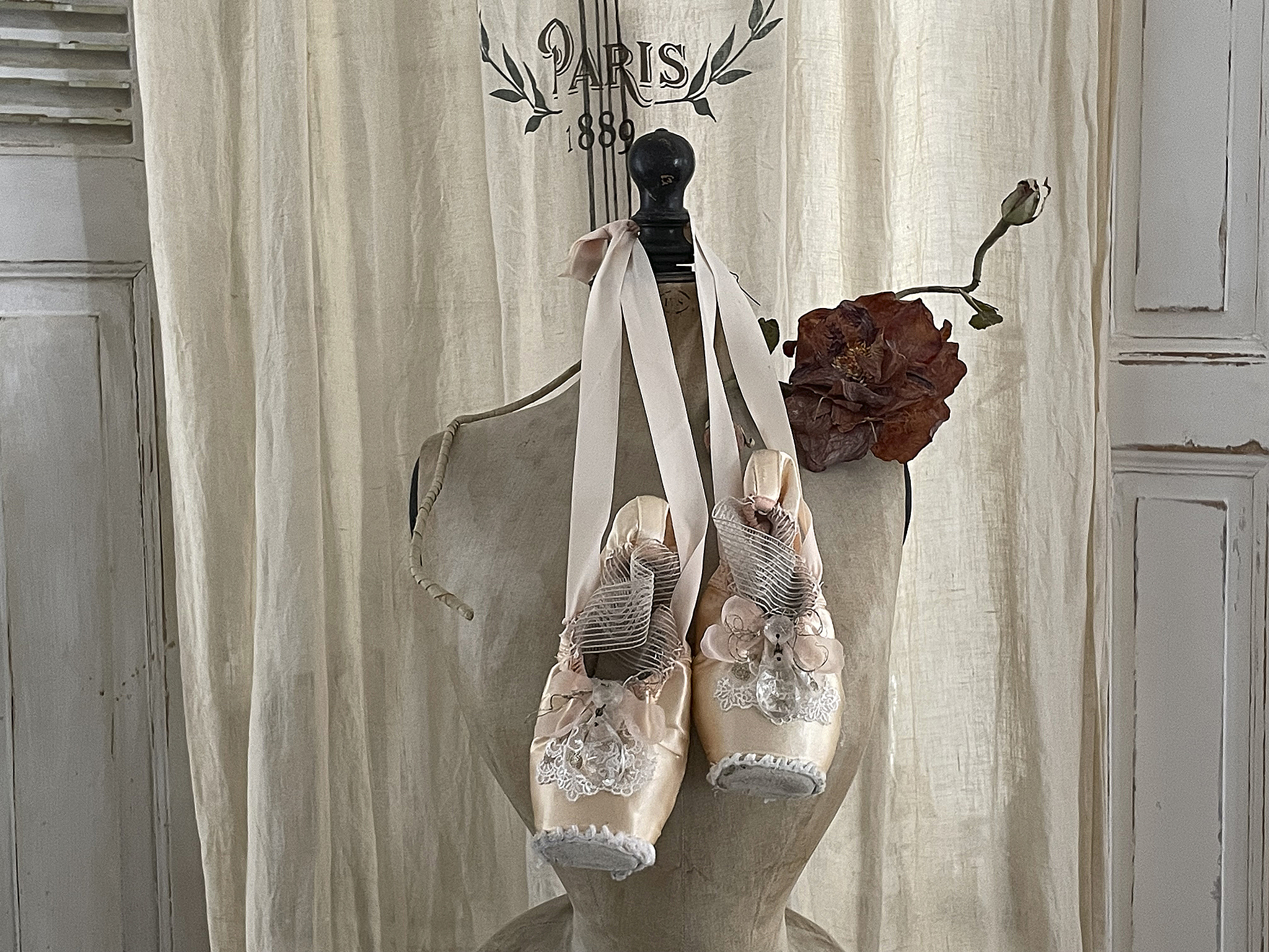 Elegante Ballettschuhe auf einer Mannequin-Statue Zarte Ballettschuhe mit Riemchen und hübscher Dekoration, präsentiert auf einer Mannequin-Statue in einem stilvollen Raum.