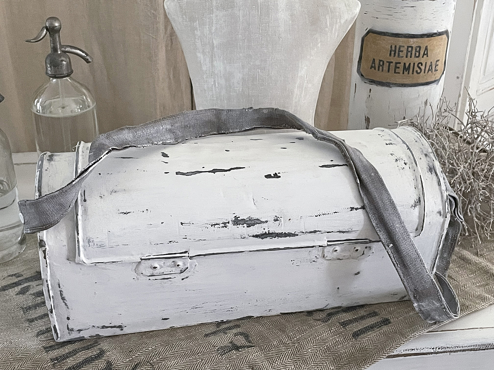 Stilvolle weiße Aufbewahrungstasche mit Tragegurt Weiße Aufbewahrungstasche im Vintage-Stil auf einem Tisch