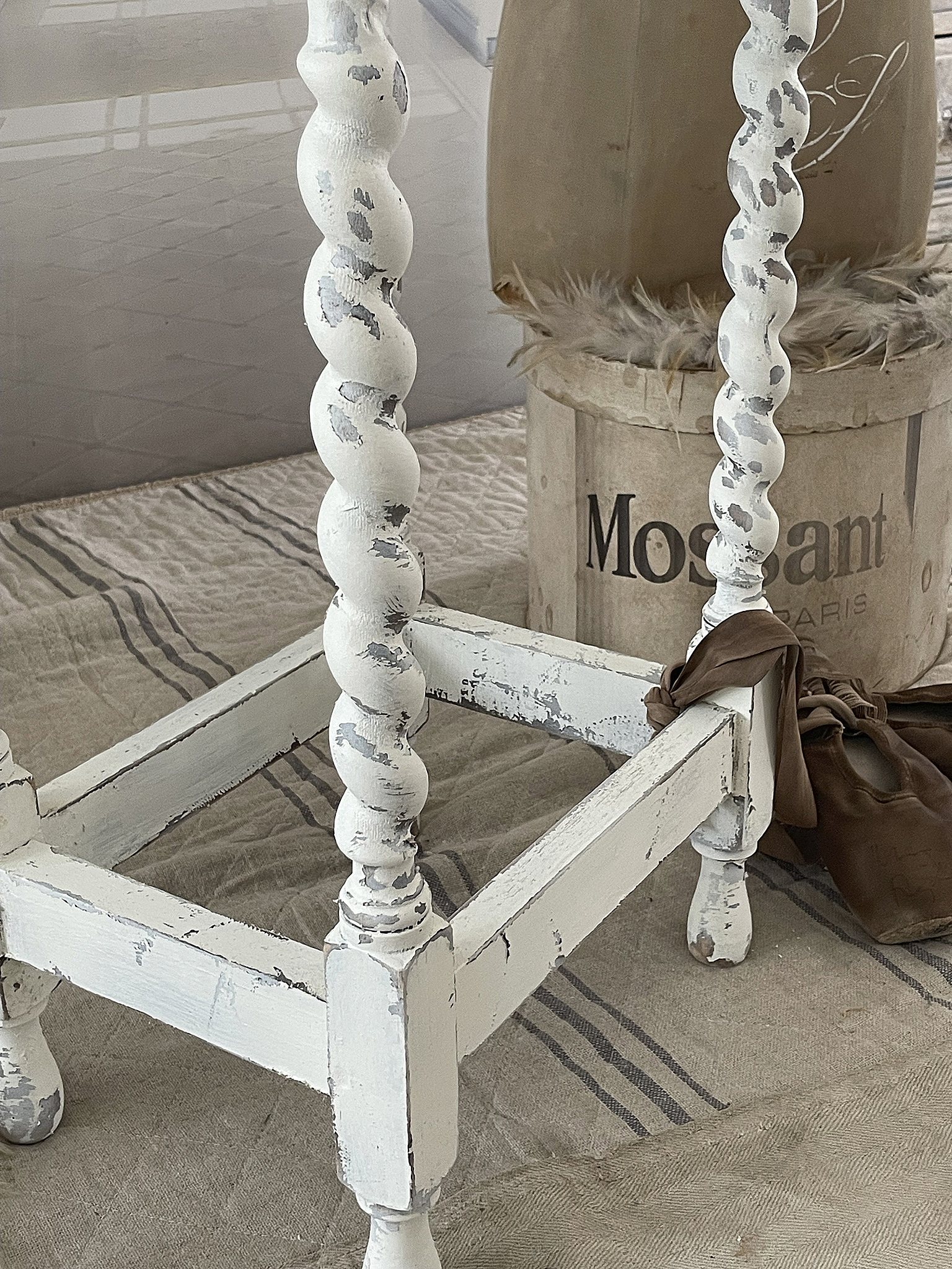 Detailaufnahme eines Vintage-Tisches mit gedrechselten Beinen Vintage-Tisch mit eingerissener weißer Farbe und gedrechselten Beinen