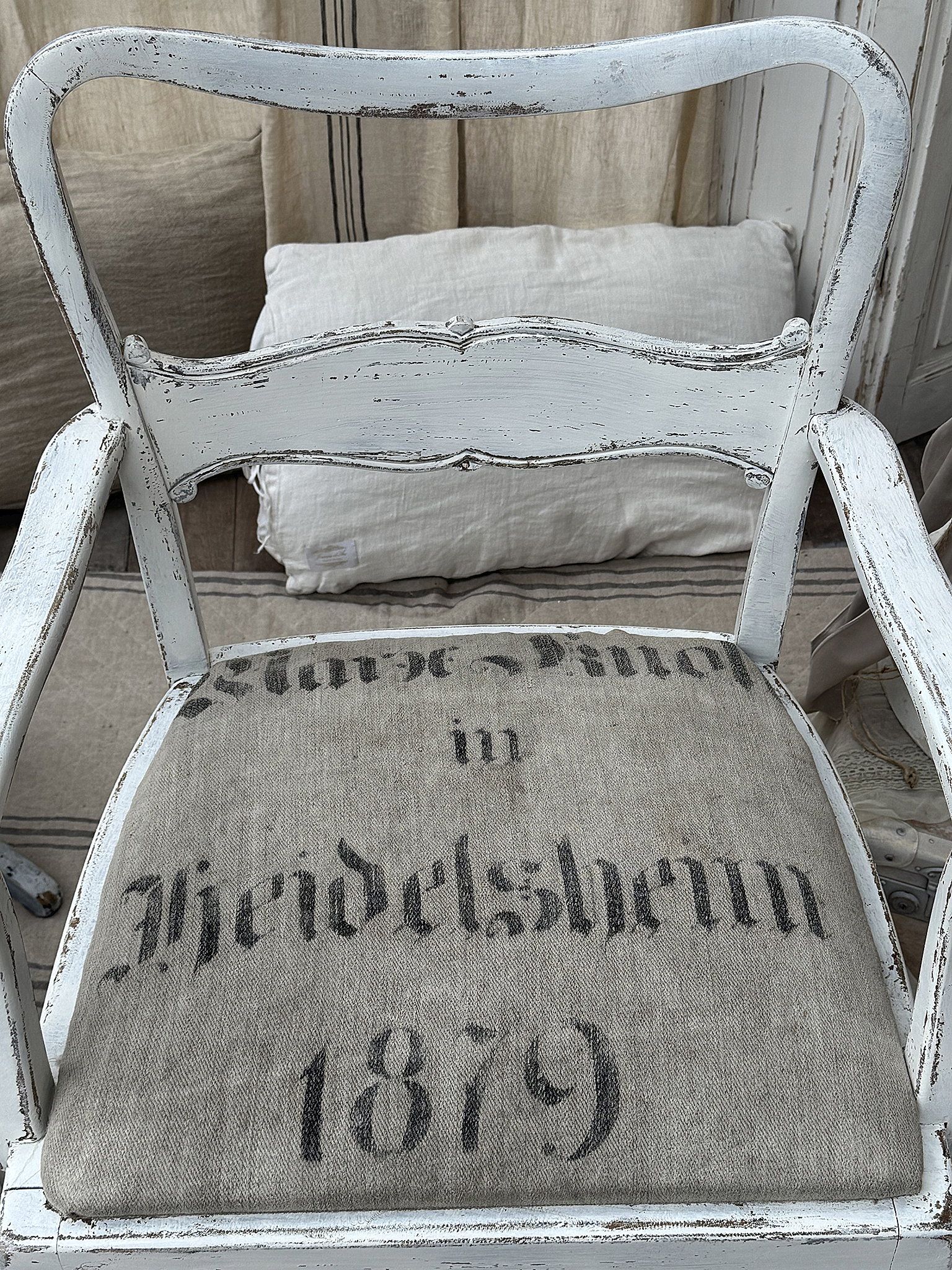 Antiker Stuhl mit aufwändiger Polsterung aus Heidelsheim 1879 Ein nostalgischer Stuhl mit vermodertem Weiß und einem Polster, das Heidelsheim 1879 zeigt.