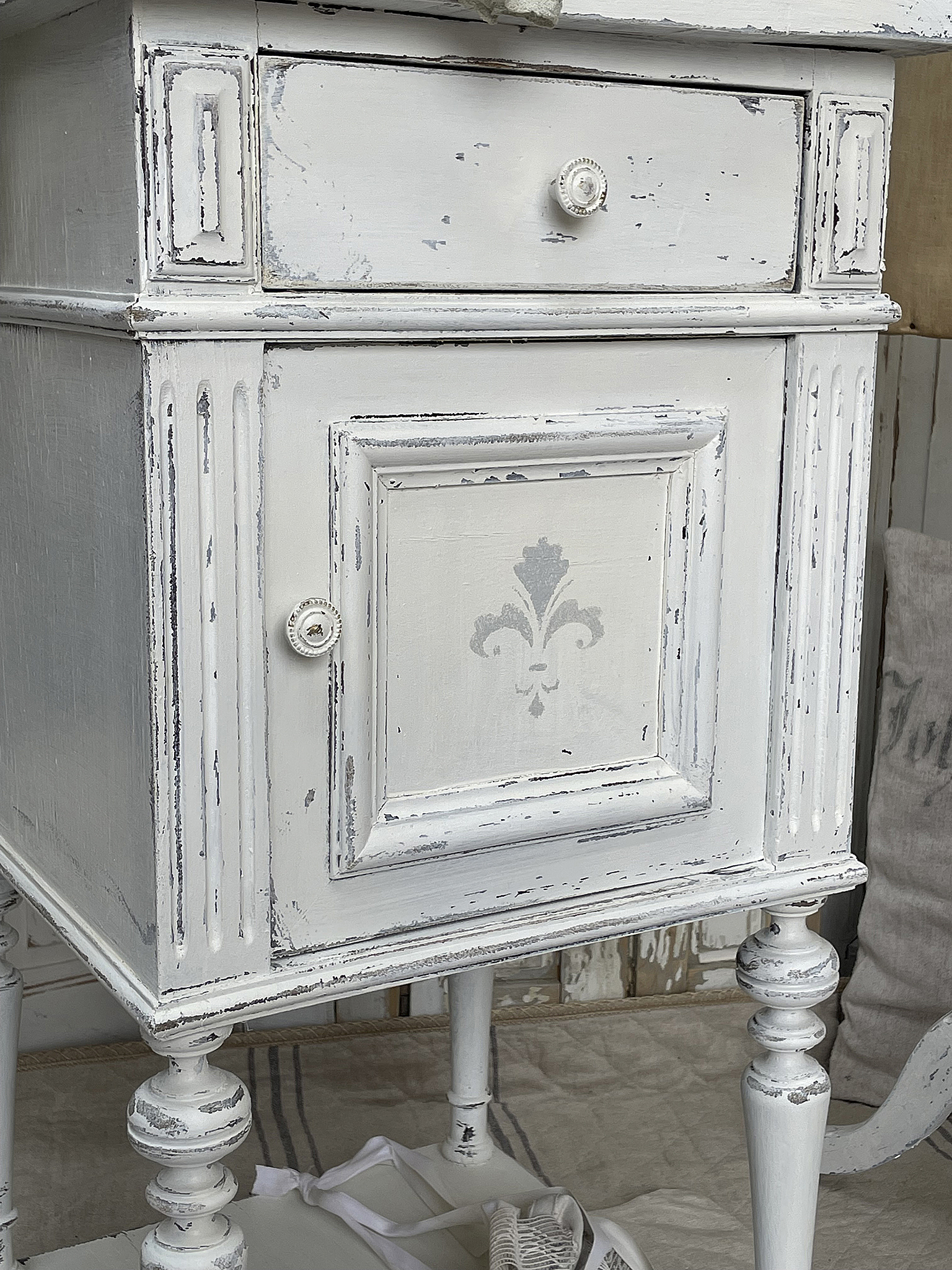 Vintage Nachttisch im Shabby Chic Design Detailaufnahme eines weißen vintage Nachttisches mit einer Schublade und einem geschwungenen Design