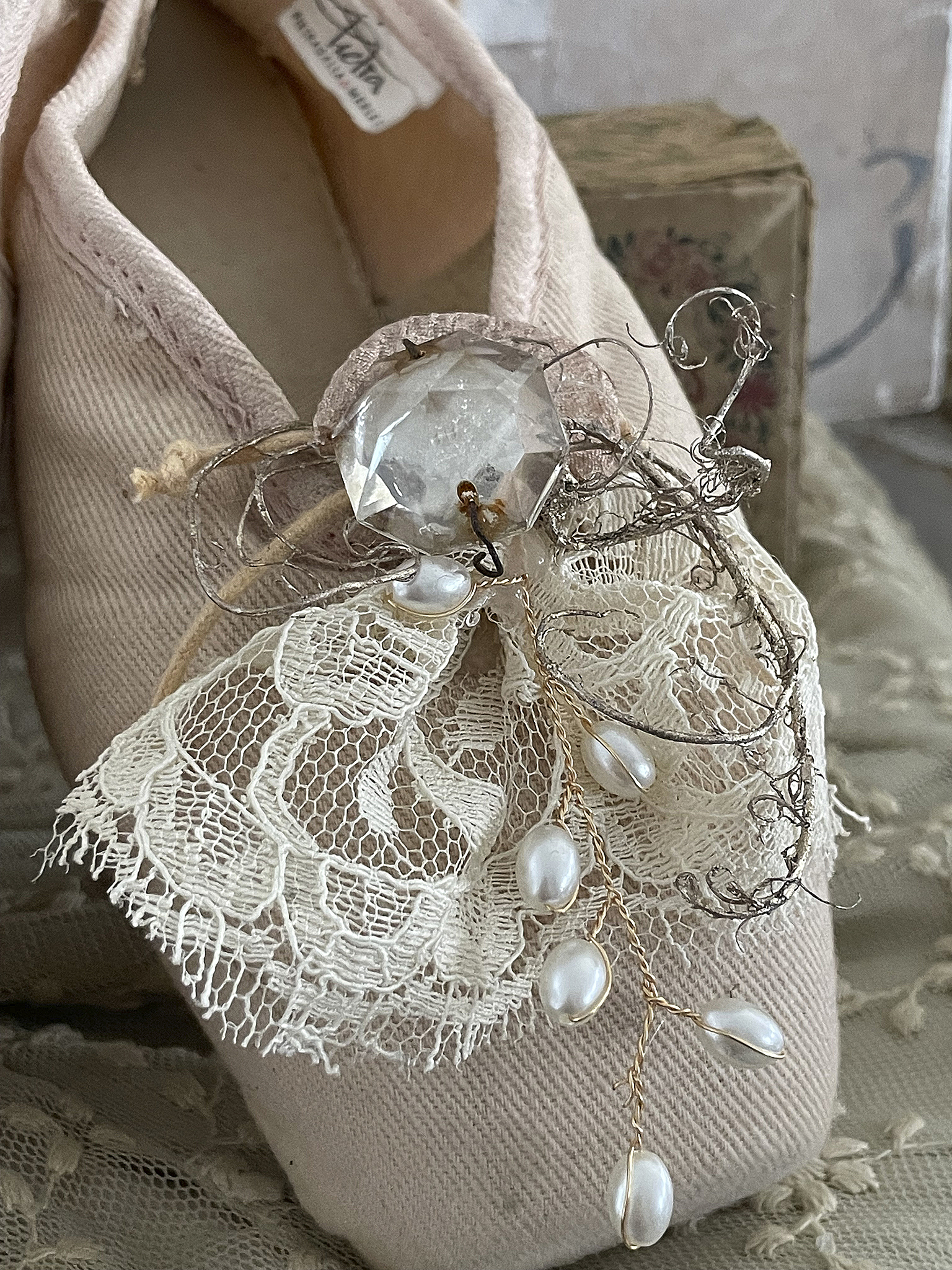 Elegante Ballettschuhe mit Verzierungen aus Spitze und Perlen Detailaufnahme eines Ballettschuhs mit dekorativer Spitze, Perlen und einem Kristallanhänger