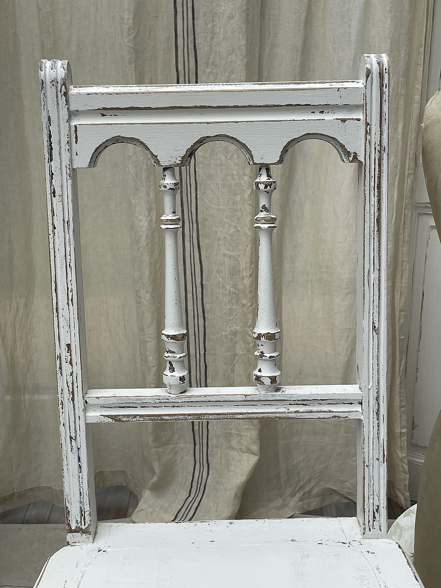 Antiker weißer Stuhl mit vintage Details Nahaufnahme eines antiken weißen Stuhls mit verzierten Rückenlehne und abgenutzten Holzdetails