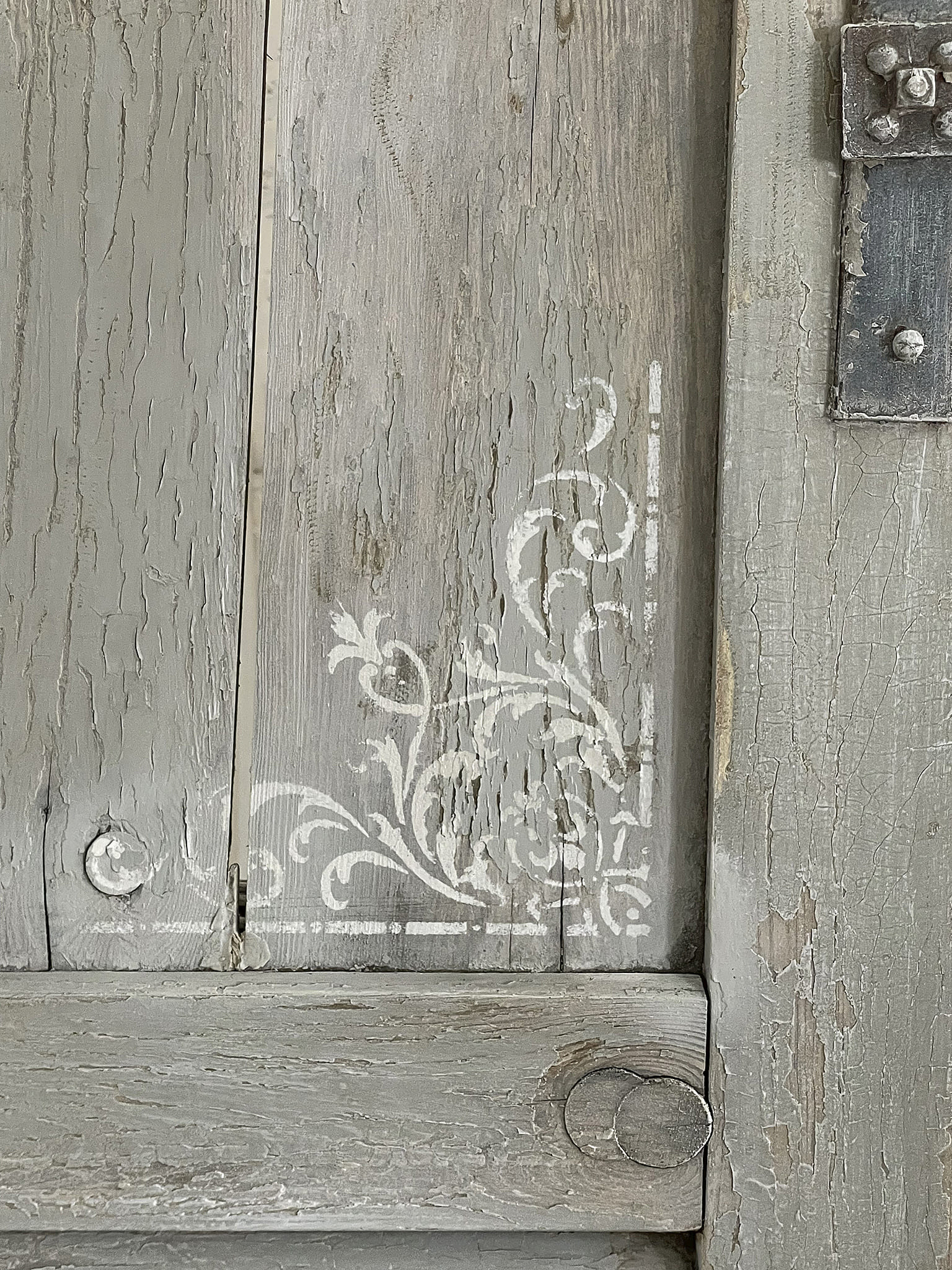 Dekoratives Holztürdesign mit filigraner Verzierung Detail einer Holztür mit grauem Anstrich und floraler Malerei