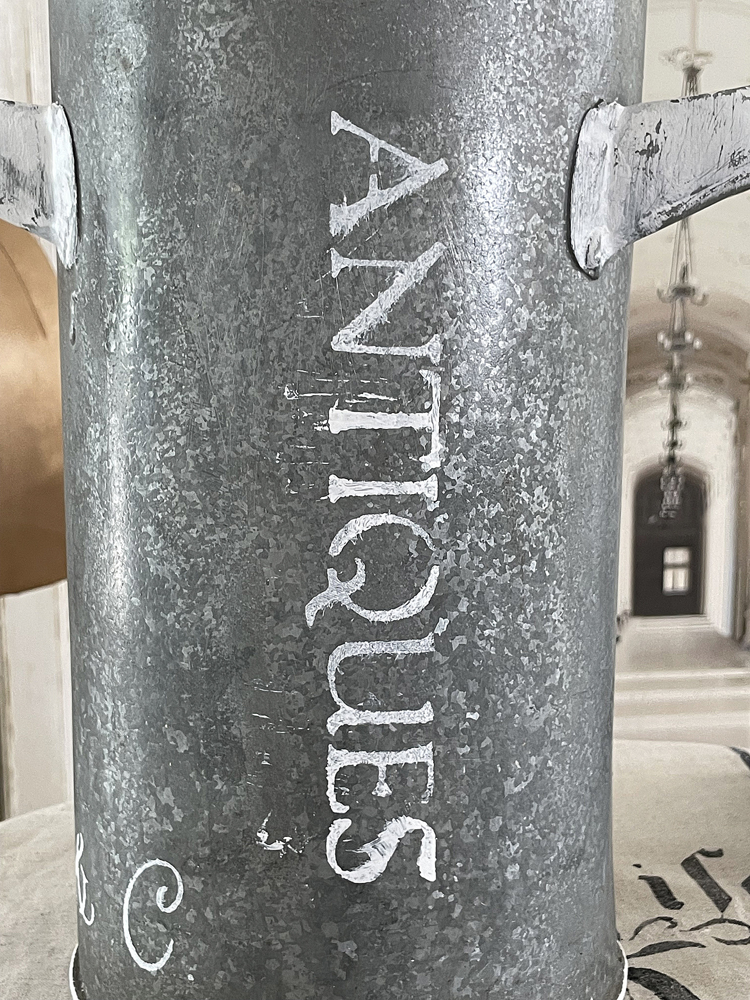 Antiker Eimer mit dem Schriftzug 'Antiques' Detailaufnahme eines antiken Eimers aus Metall mit Aufschrift 'Antiques'