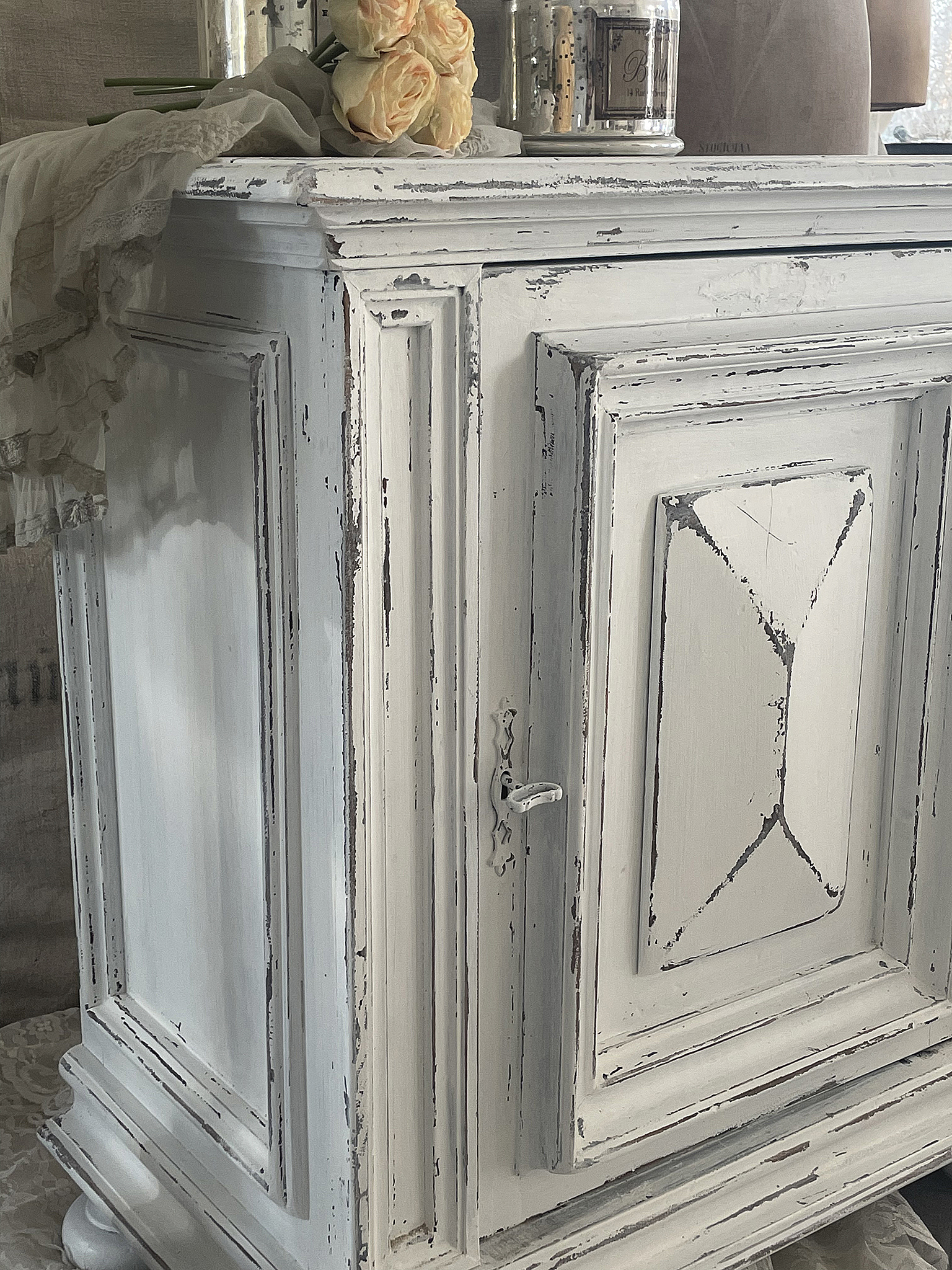 Detailaufnahme eines vintage weißen Sideboards im Shabby-Chic-Stil mit Blumen und Dekoration