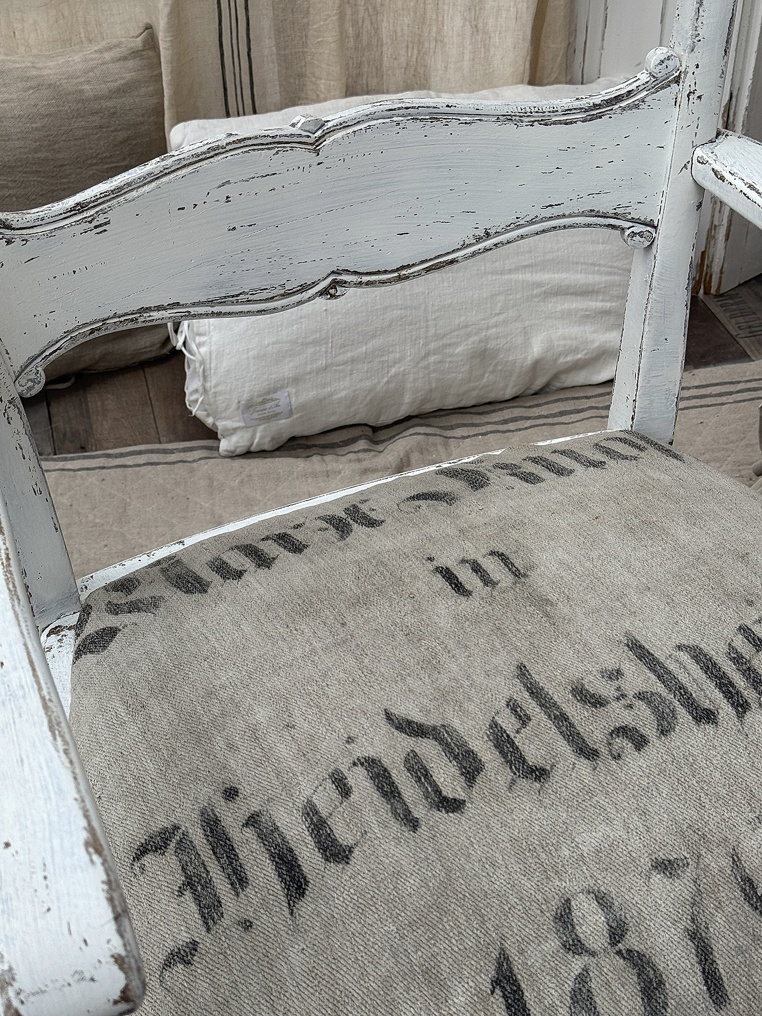 Vintage Stuhl mit Leinensitz und alten Buchstaben Detailaufnahme eines vintage Stuhls mit einem Leinensitz, auf dem alte Buchstaben aufgedruckt sind.