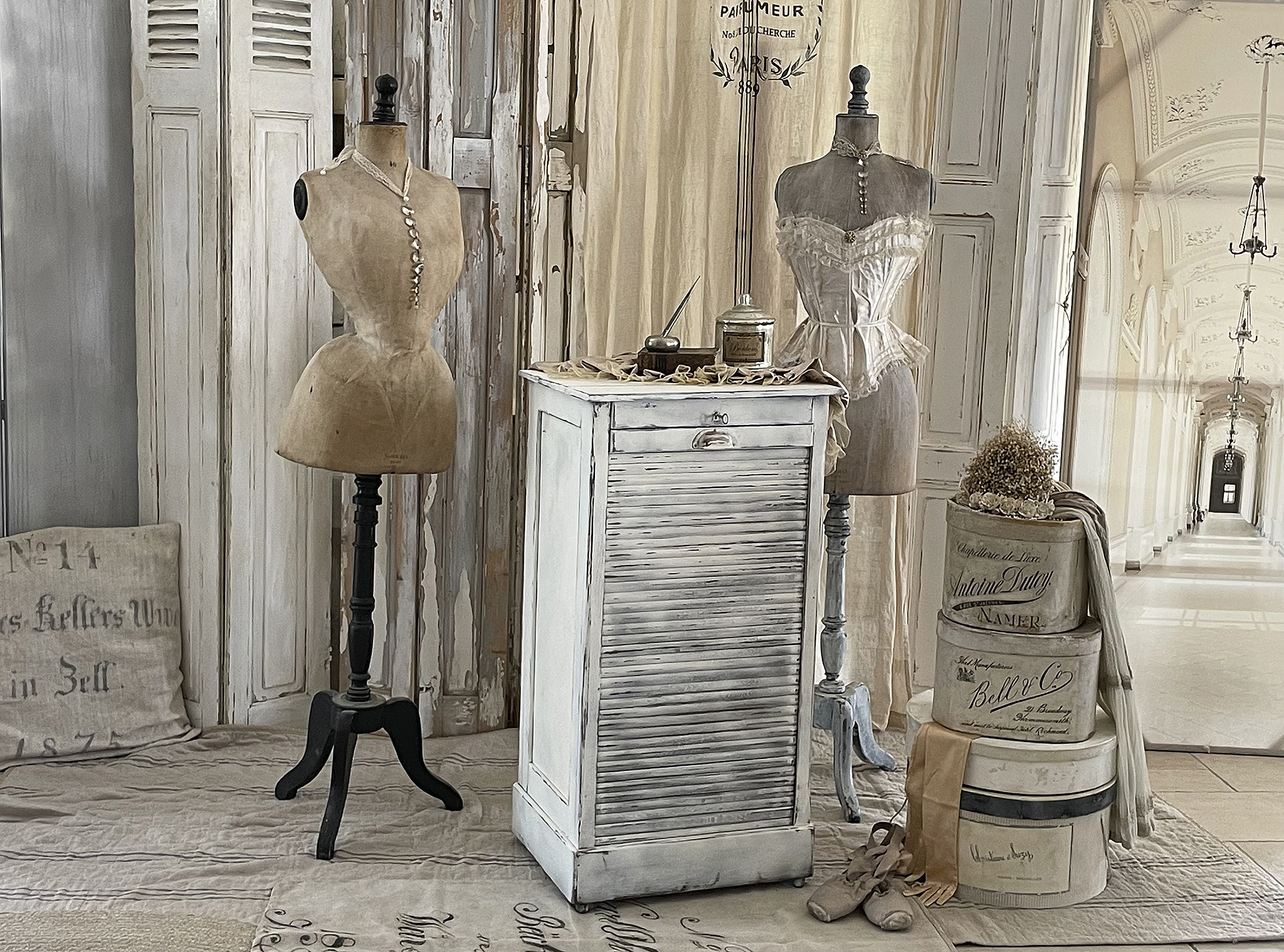 Vintage Schneiderpuppe und antiker Tisch im eleganten Raum Antiker Tisch mit Schneiderpuppen und Dekoration in stilvollem Innenraum