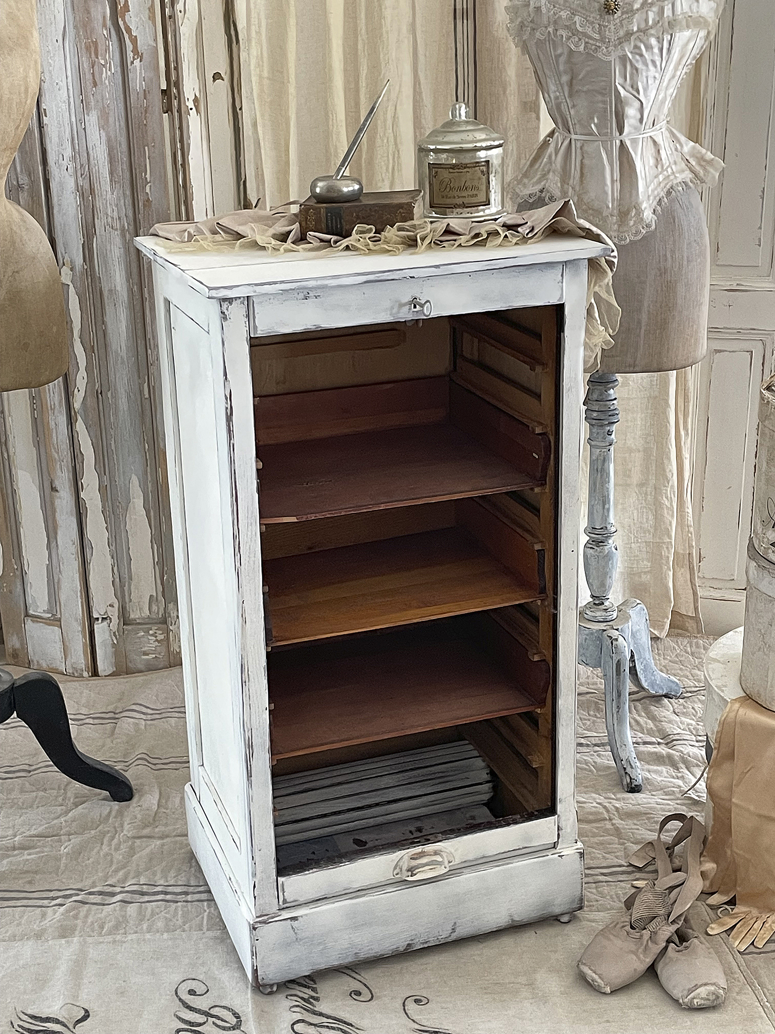 Antiker Schrank mit offenen Regalböden und Dekoration Antiker Schrank mit Holzregalen, einer Schreibfeder, einem Glasbehälter und dekorativen Stoffen