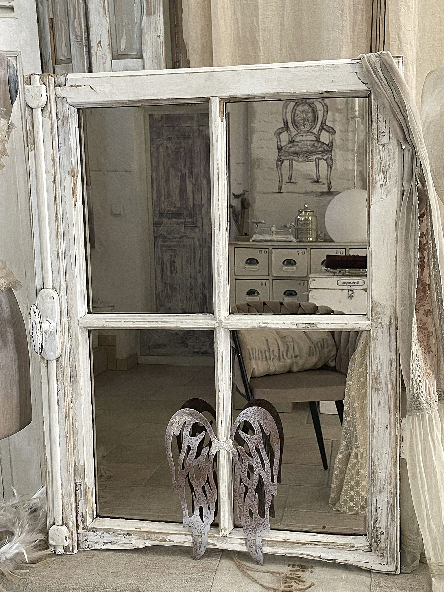 Vintage Fenster mit dekorativen Flügeln im Innenraum Ein altes, weißes Fenster mit Flügel-Dekorationen und einem Blick auf einen stilvollen Innenraum.