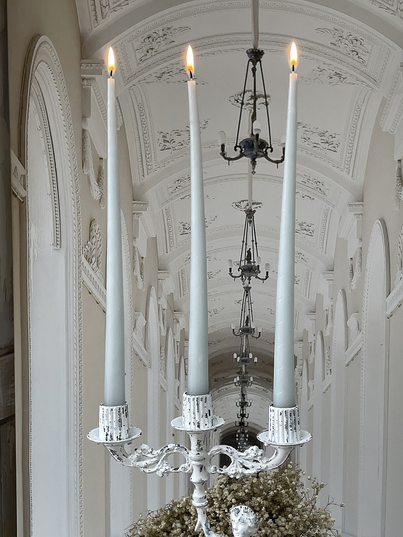 Eleganter Kerzenständer mit weißen Kerzen und stilvollem Hintergrund Kerzenständer mit drei weißen brennenden Kerzen in hellem, eleganten Raum