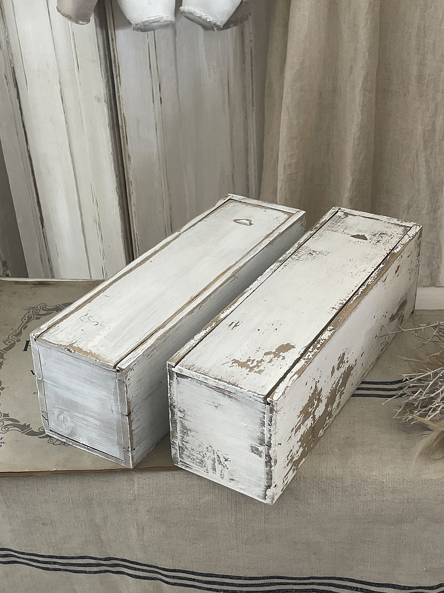 Zwei weiß lackierte Holzkisten im shabby-chic Design auf einem Tisch