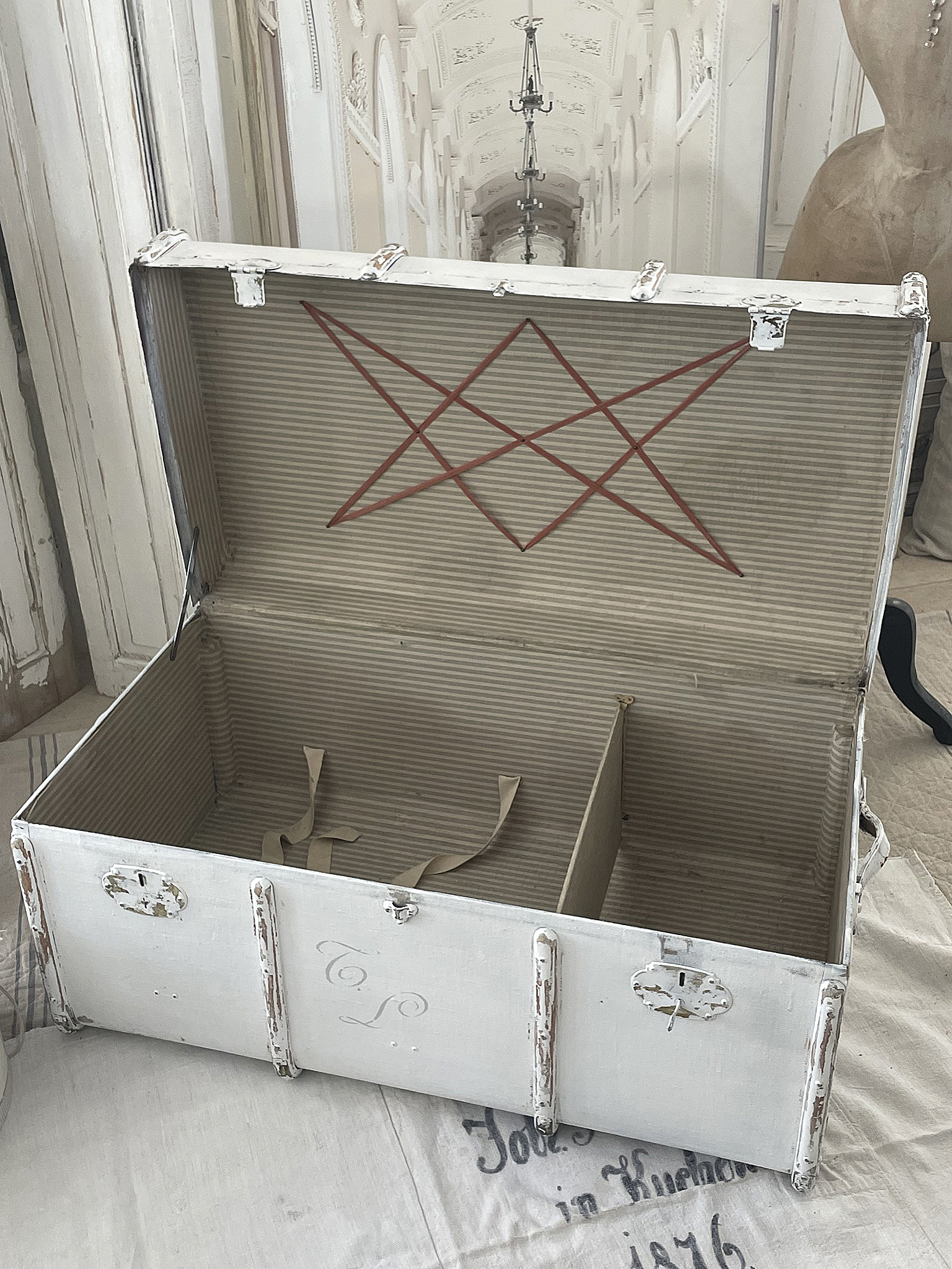 Offene Vintage Truhe aus Holz mit gestreiftem Innenfutter und Unterteilungen.