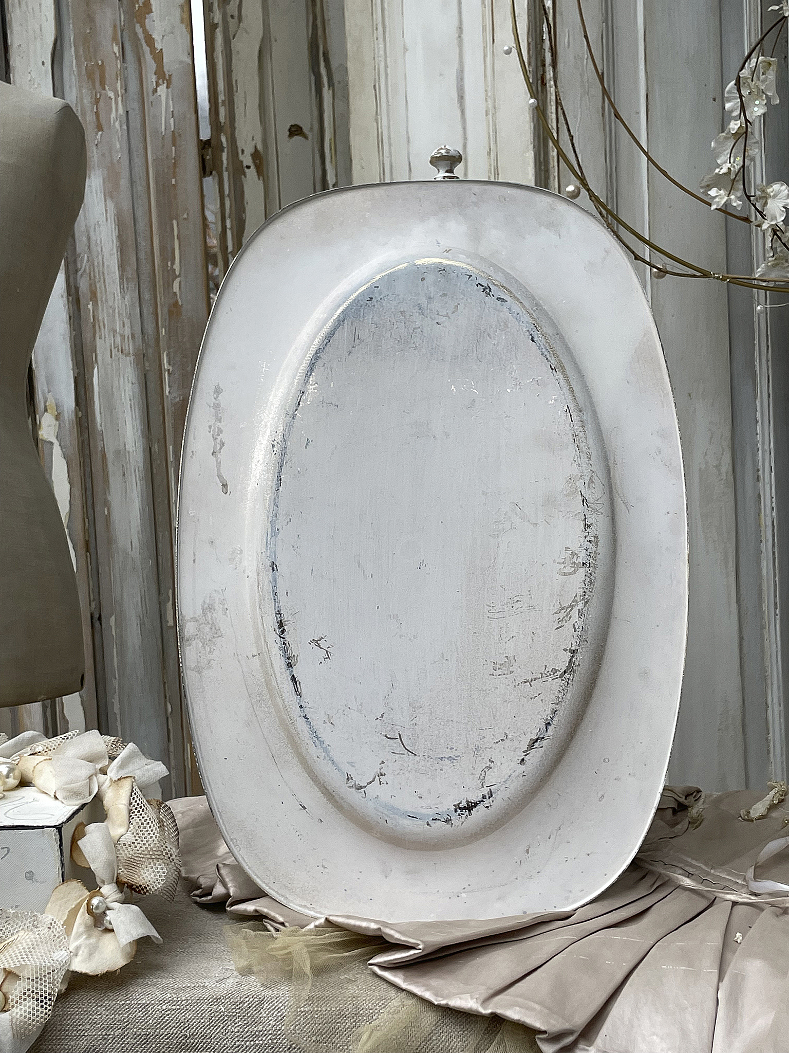 Weiße ovalförmige Servierplatte auf einem gedeckten Tisch, umgeben von Dekorationen