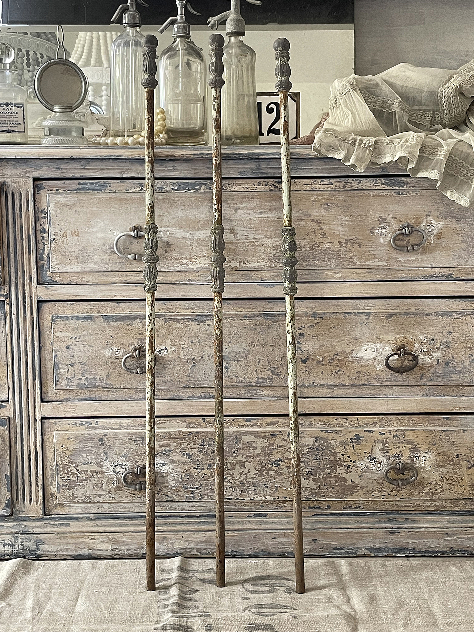 Antike Holzstäbe für Dekoration oder Handwerk Drei antike Holzstäbe vor einer rustikalen Kommode, ideal für Vintage-Dekoration.
