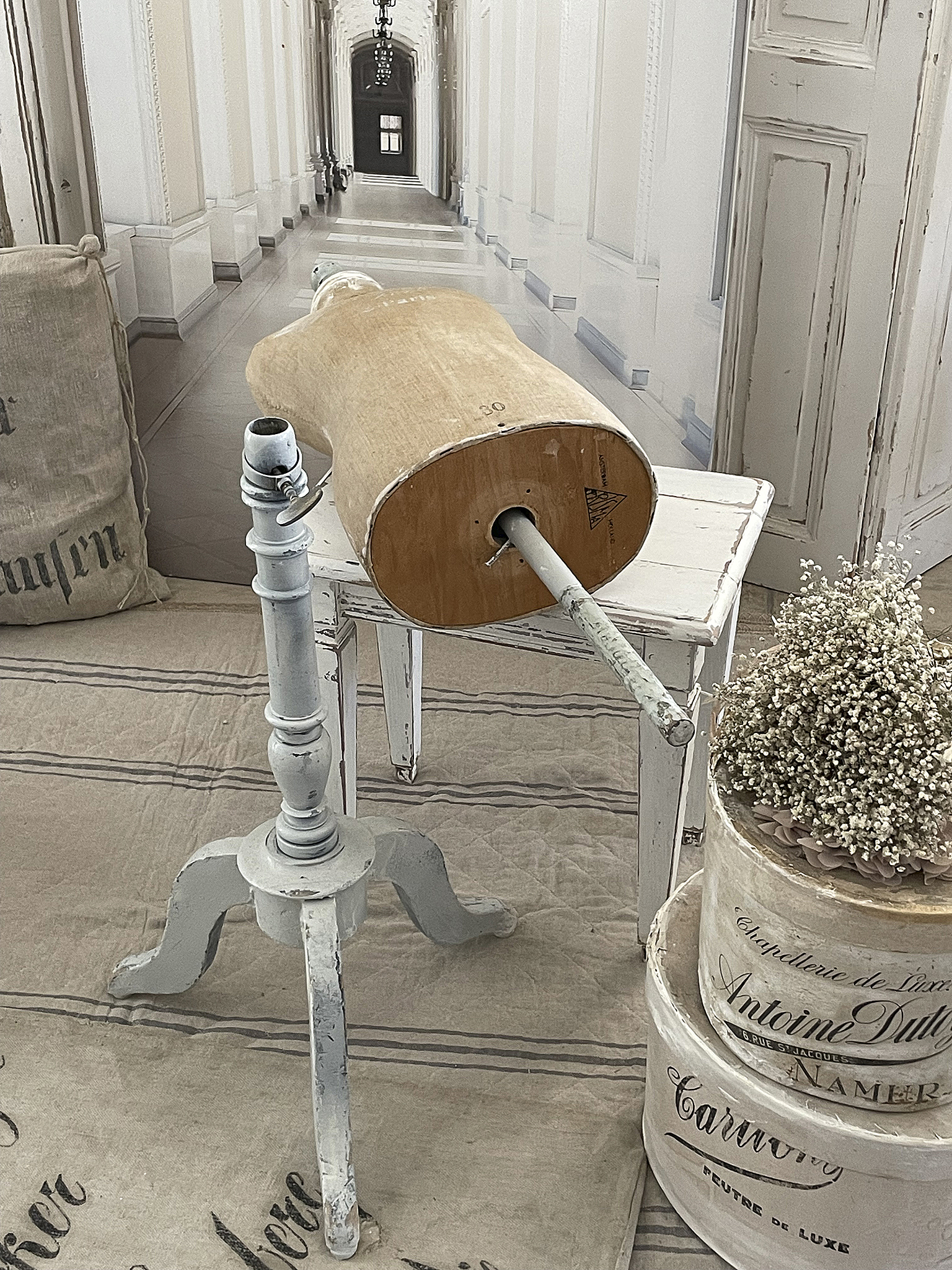 Vintage Schneiderpuppe auf rustikalem Tisch in stilvollem Raum Detailaufnahme einer vintage Schneiderpuppe auf einem weißen Tisch, umgeben von Dekorationen