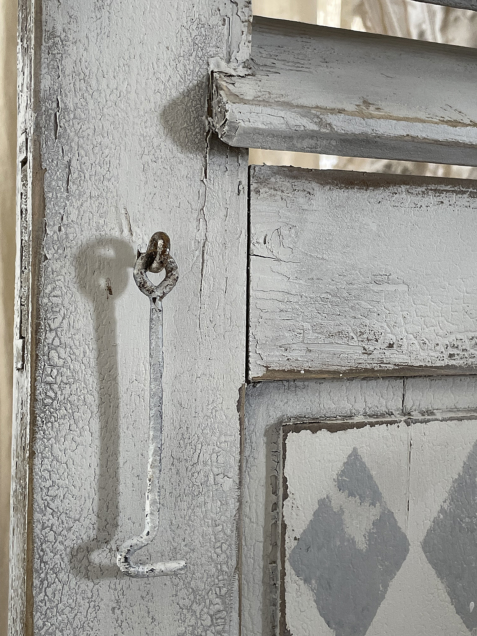 Rustikales Holztor mit veraltetem Beschlag und einzigartigem Design Nahaufnahme eines rustikalen Holztores mit weißen Farbablättern und einem speziellen Beschlag
