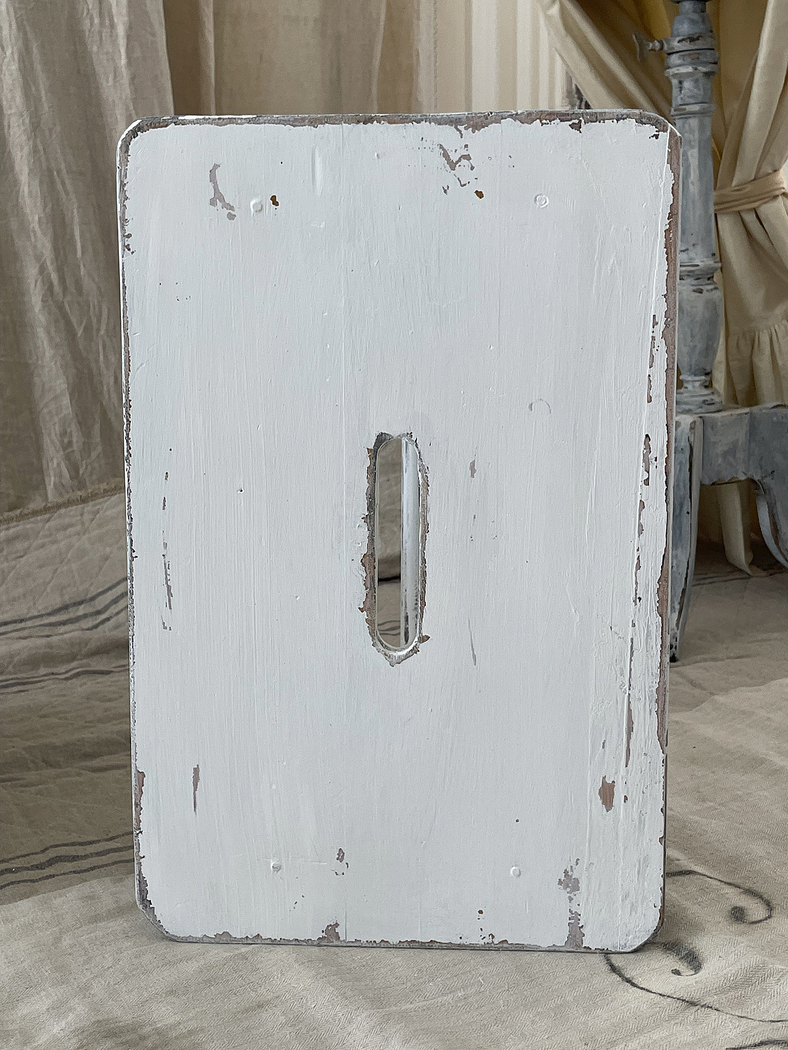 Rustikales Holzschild in Weiß mit Gebrauchsspuren Weißes Holzschild mit einem Schlitz in der Mitte und sichtbaren Gebrauchsspuren