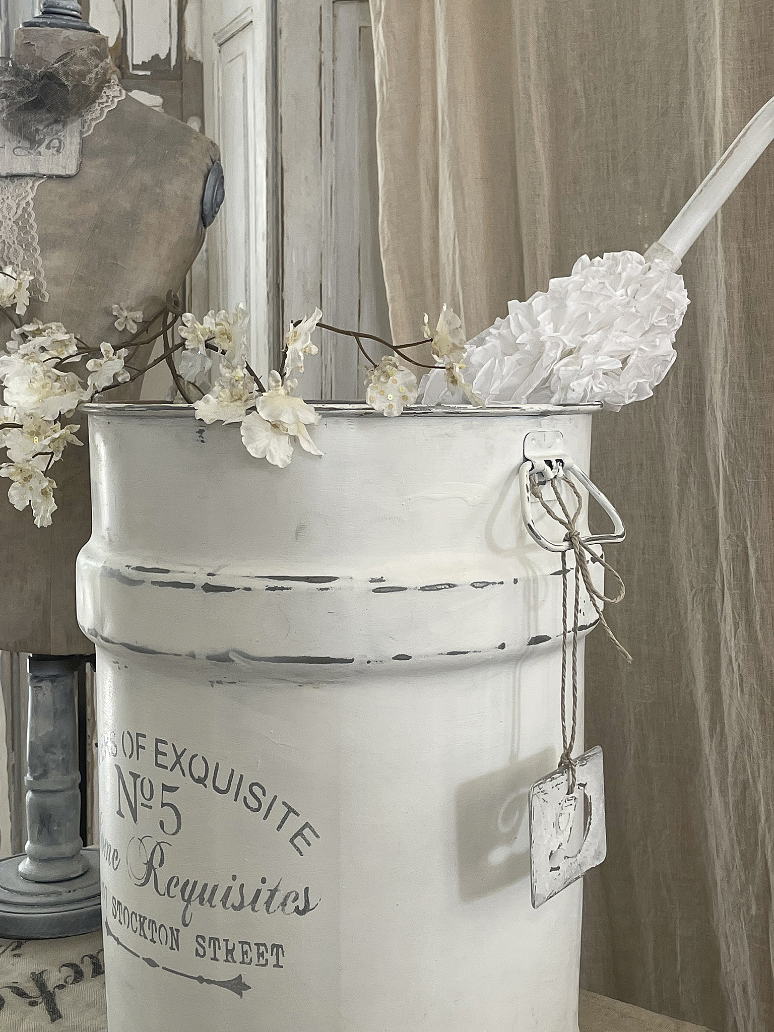 Dekorativer Eimer mit weißen Blumen und Staubtuch Dekorativer weißer Eimer mit Blumen und Staubtuch im Vintage-Stil