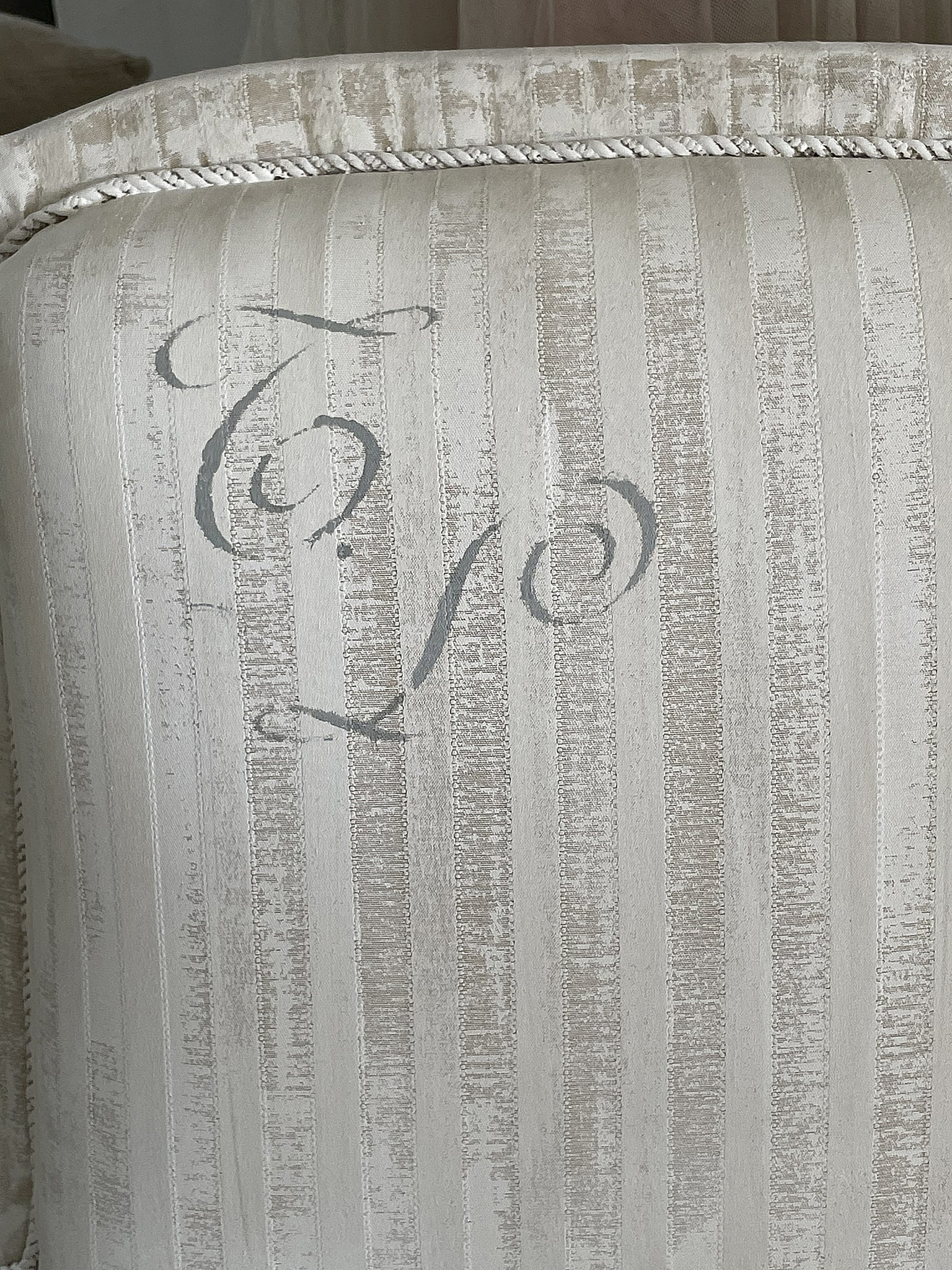 Detailansicht eines eleganten Kissens mit feinen Streifen und einer stilisierten Schrift.