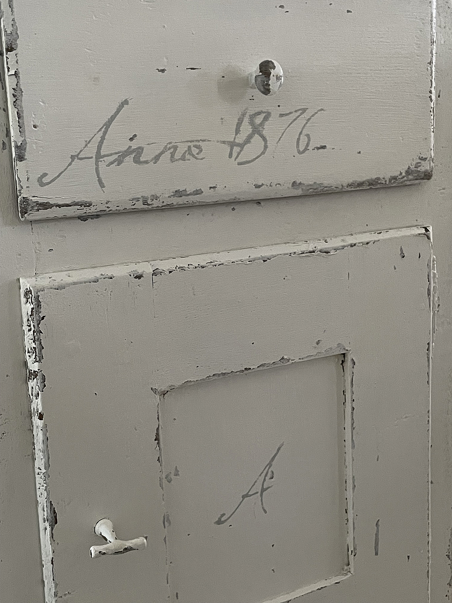 Antiker Schrank mit Handgeschriebenem von 1876 Detailaufnahme eines antiken Schranks mit der Inschrift 'Aino 1876' und einem geschliffenen Finish