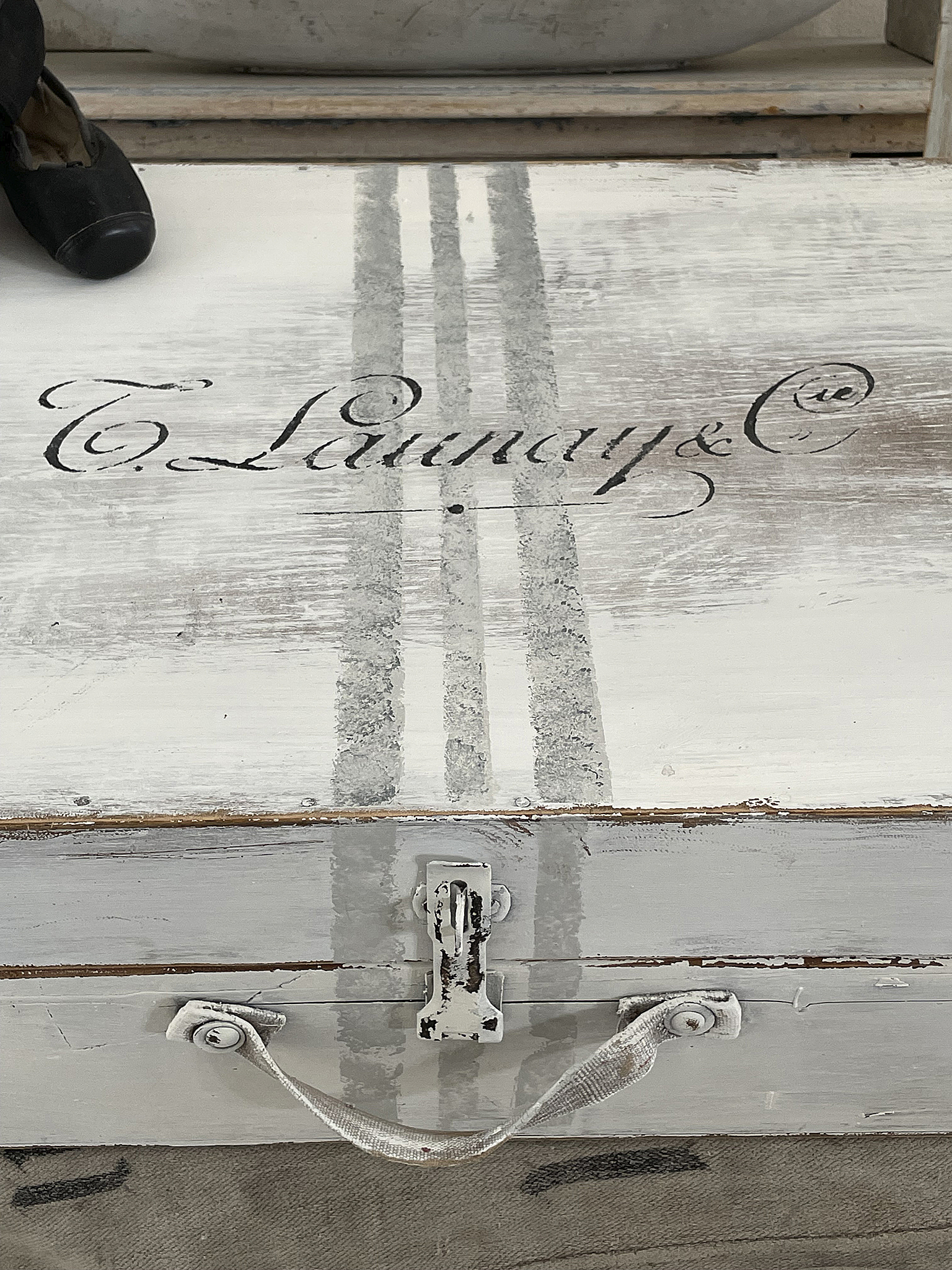 Vintage Aufbewahrungskiste mit handgemalter Schrift Detailaufnahme einer Vintage Aufbewahrungskiste mit der Aufschrift T. Launay & C. auf der Oberseite.