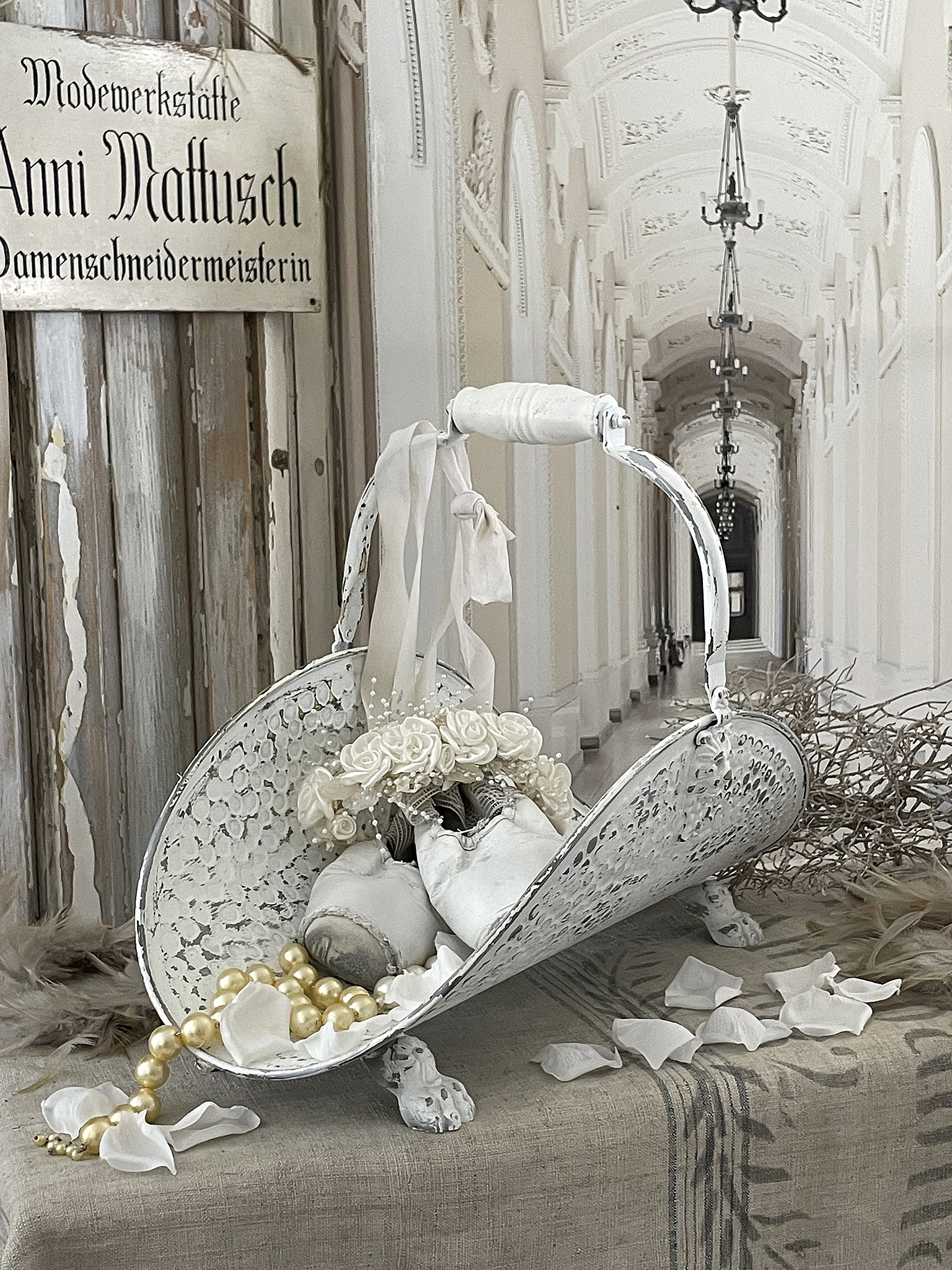 Dekorative Hochzeitsartikel mit weißen Rosen und Perlen Vintage Körbchen mit weißen Rosen, Perlen und Seidenblüten auf einem Tisch