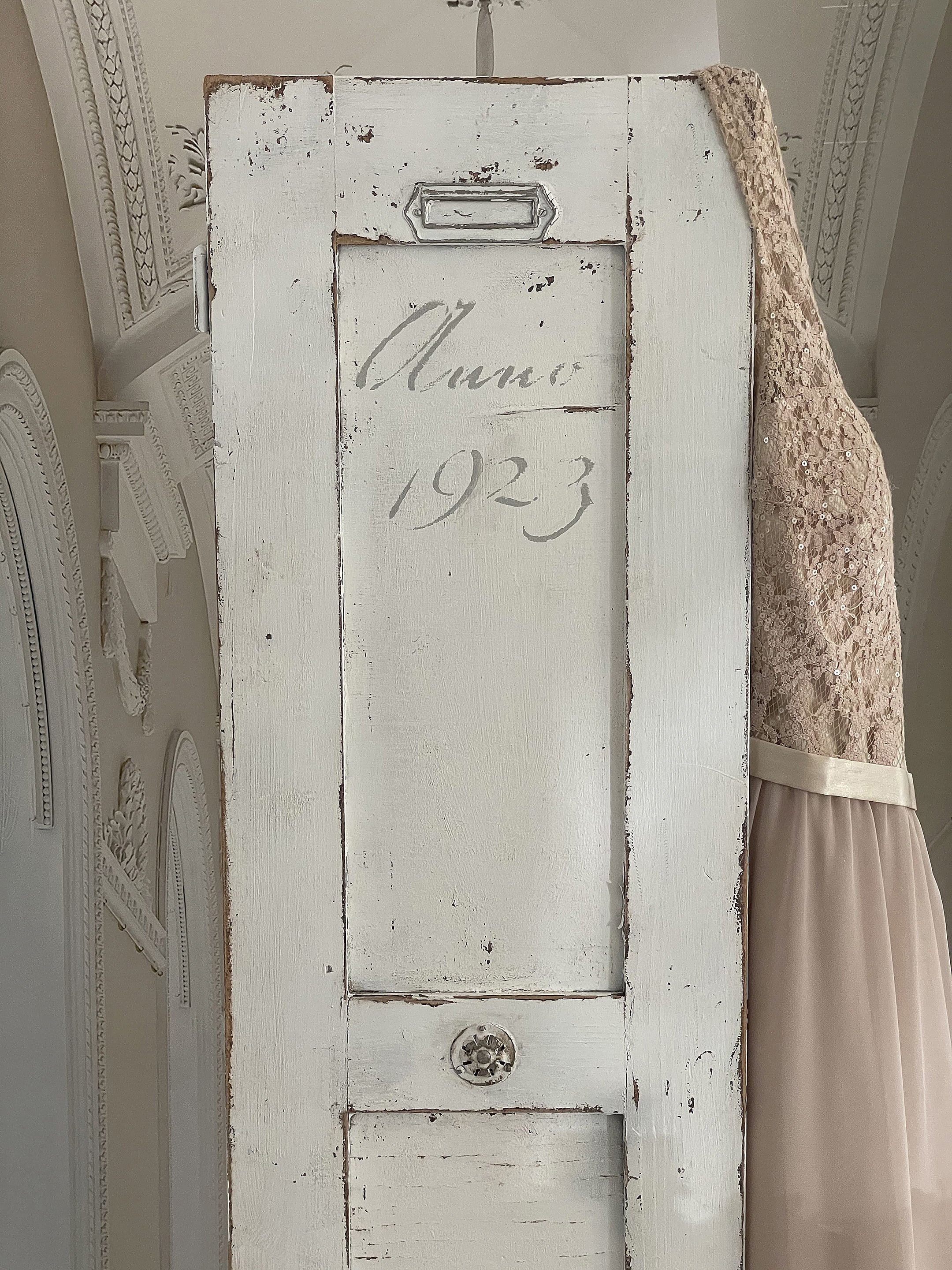 Antike Tür mit dem Jahr 1923 und vintage Kleid Antike weiße Tür mit der Aufschrift 'Anno 1923' und einem eleganten Kleid daneben