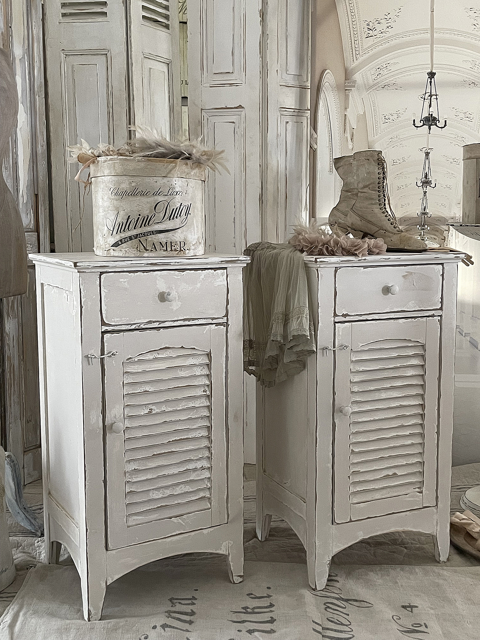 Shabby Chic Nachttische im Vintage-Stil mit feinen Details Zwei weiße, shabby chic Nachttische mit offenen Schubladen und einer dekorativen Box auf der Oberfläche.