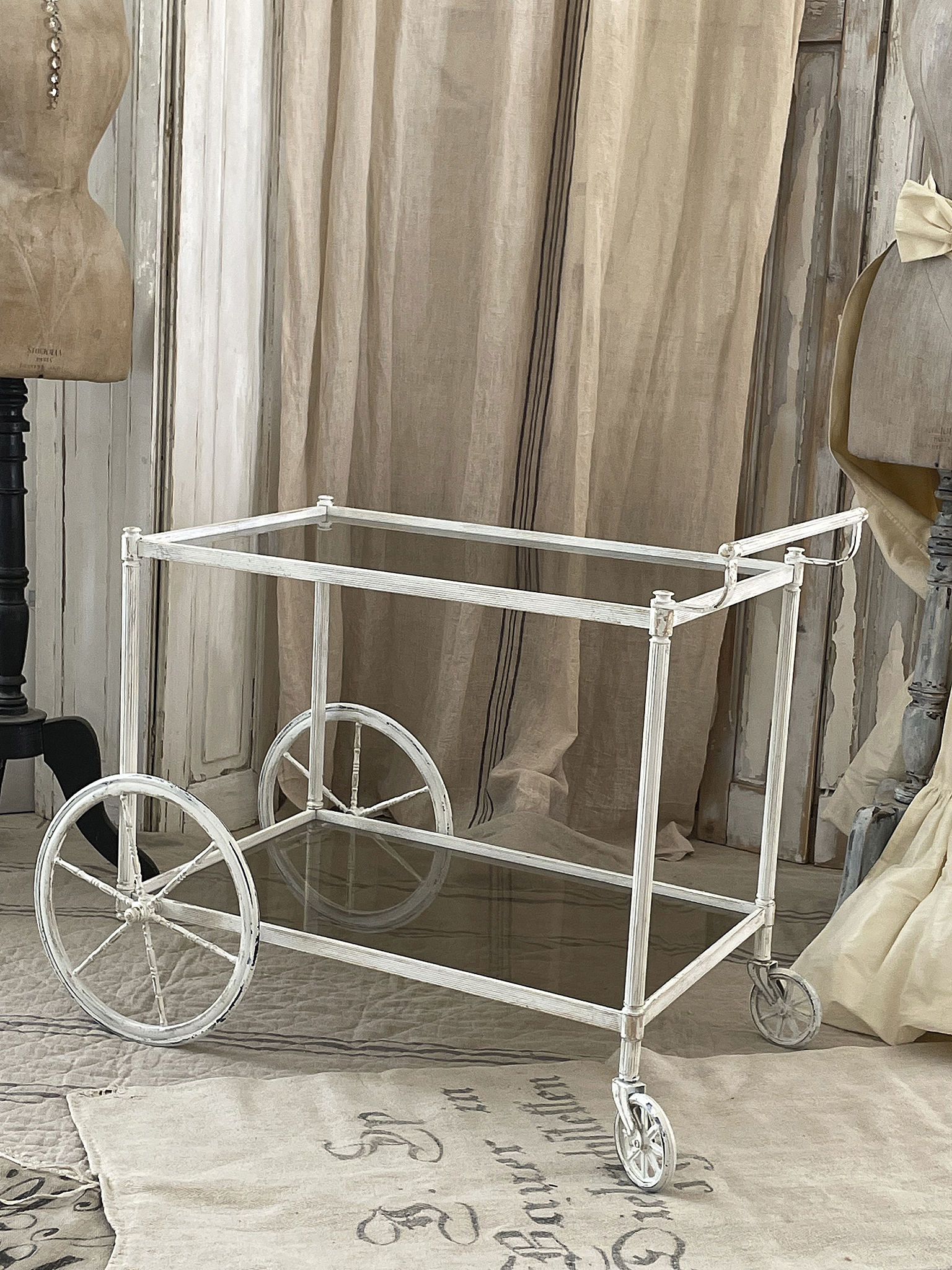 Eleganter Servierwagen aus Metall mit Glasplatte Heller Servierwagen aus Metall mit großen Rädern und Glasoberfläche im Vintage-Stil