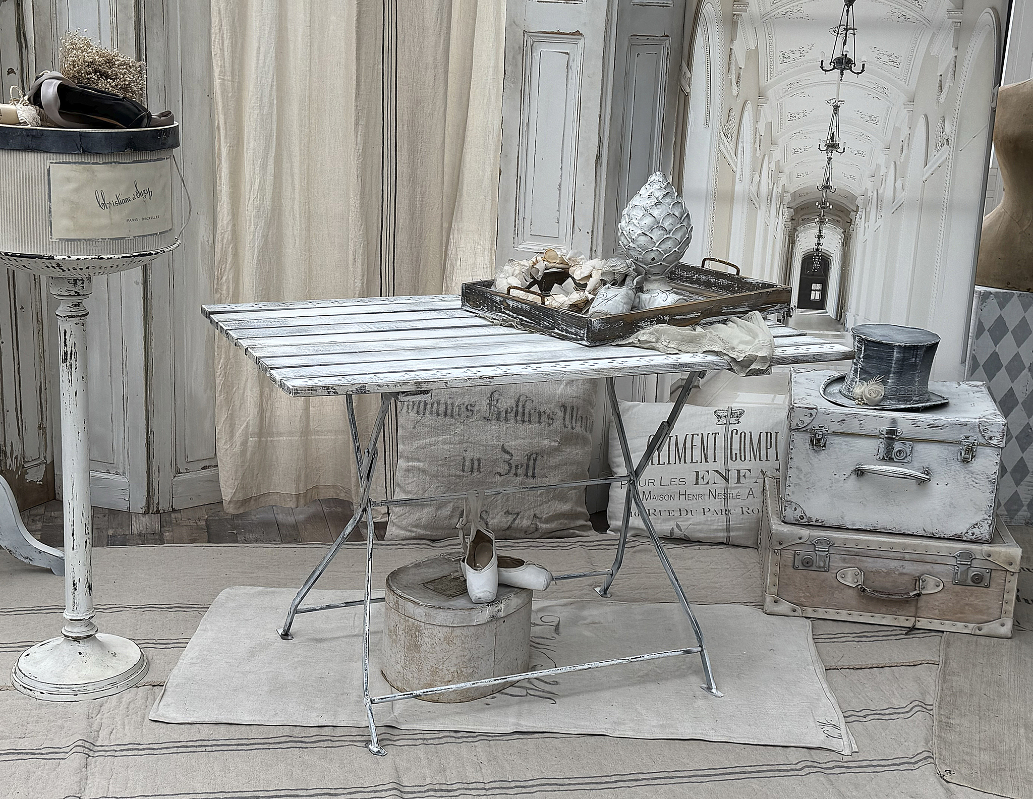 Ein shabby-chic Tisch mit Dekorationsgegenständen und einer Vase im Hintergrund, ideal für stilvolle Einrichtung.
