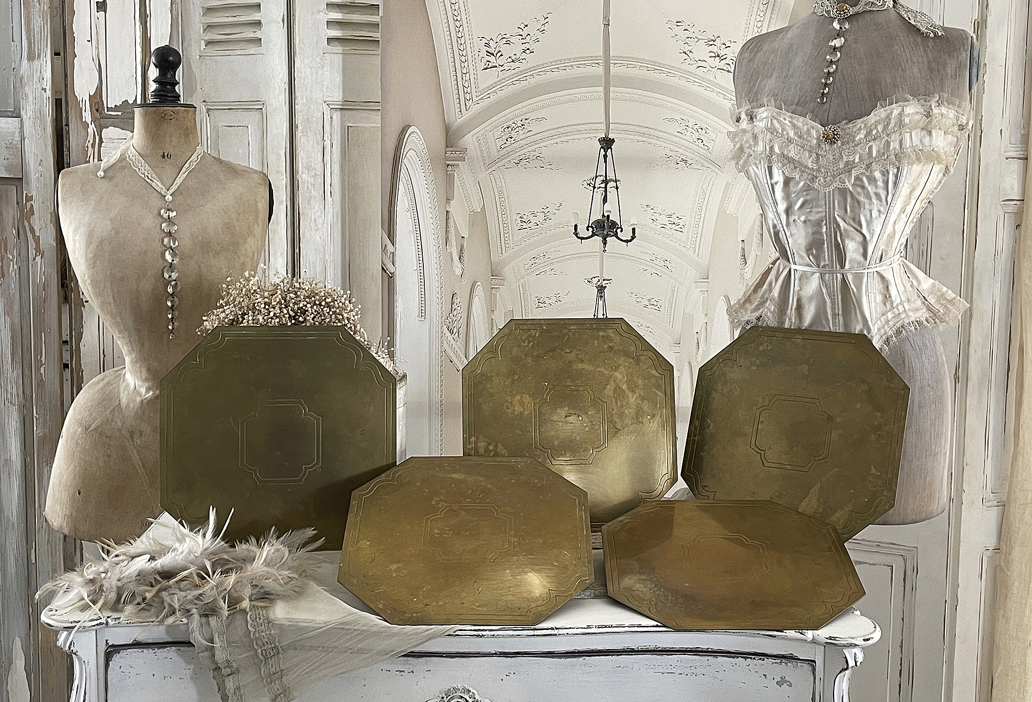 Wunderschöne antike Platzteller im Vintage-Stil Antike Platzteller aus Messing, elegant auf einem weißen Tisch präsentiert, umgeben von vintage Dekoration.
