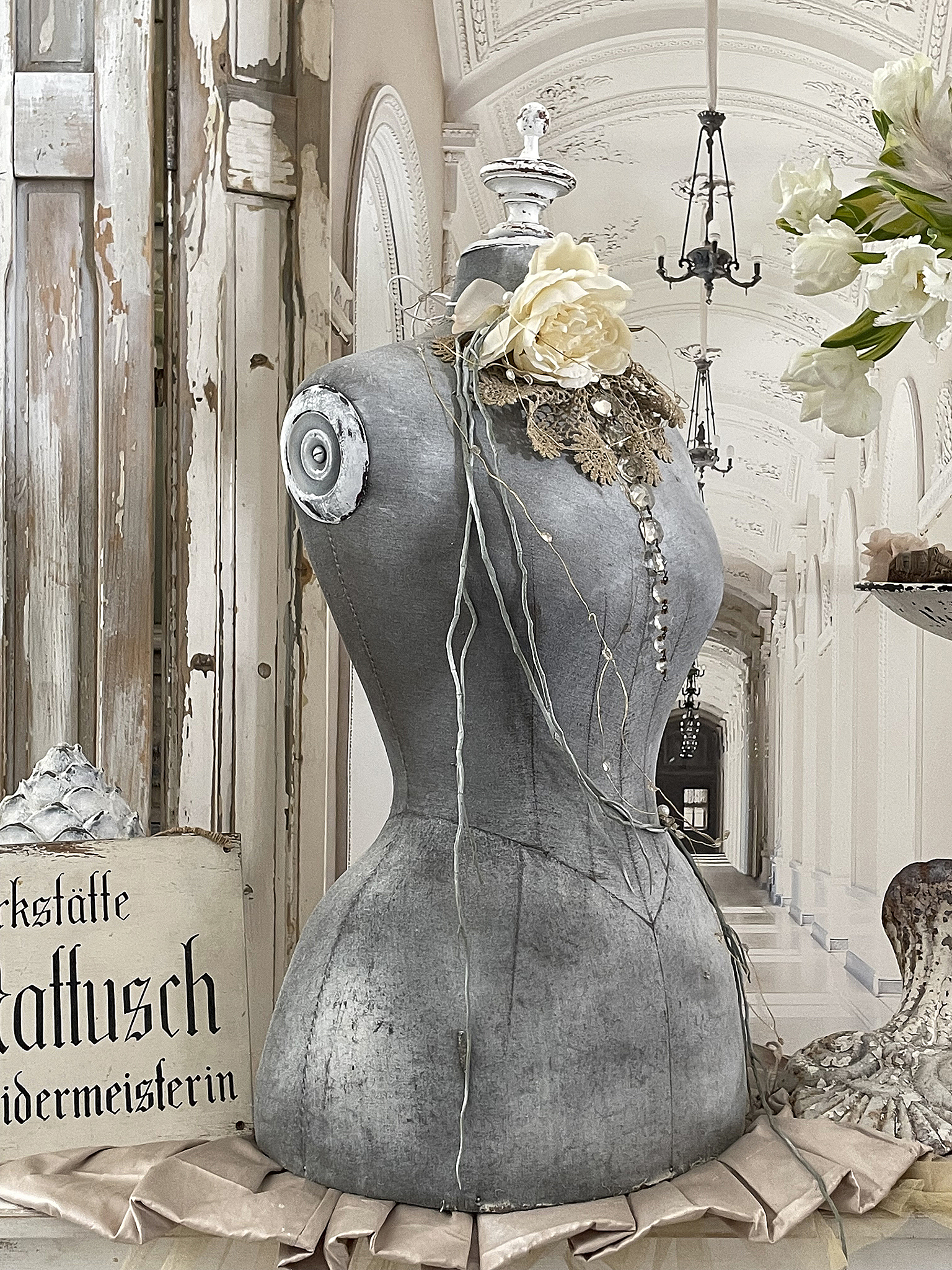 Stilvolle Schneiderpuppe mit Blüten und Spitze, dekorativ in einer eleganten Halle platziert