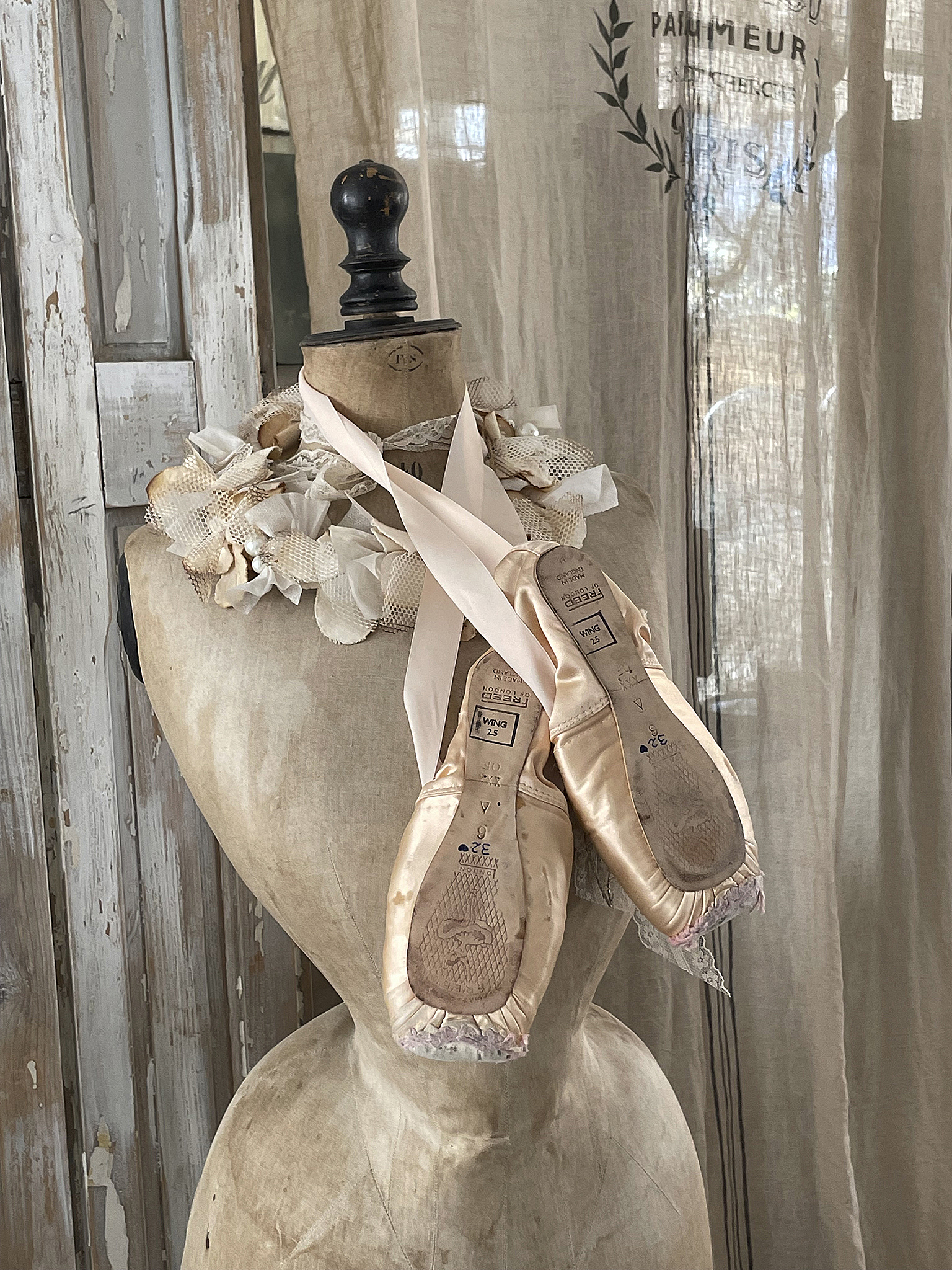Ballettschuhe mit Schleifen auf einer Schneiderpuppe Elegante Ballettschuhe auf einer Schneiderpuppe mit dekorativem Kranz