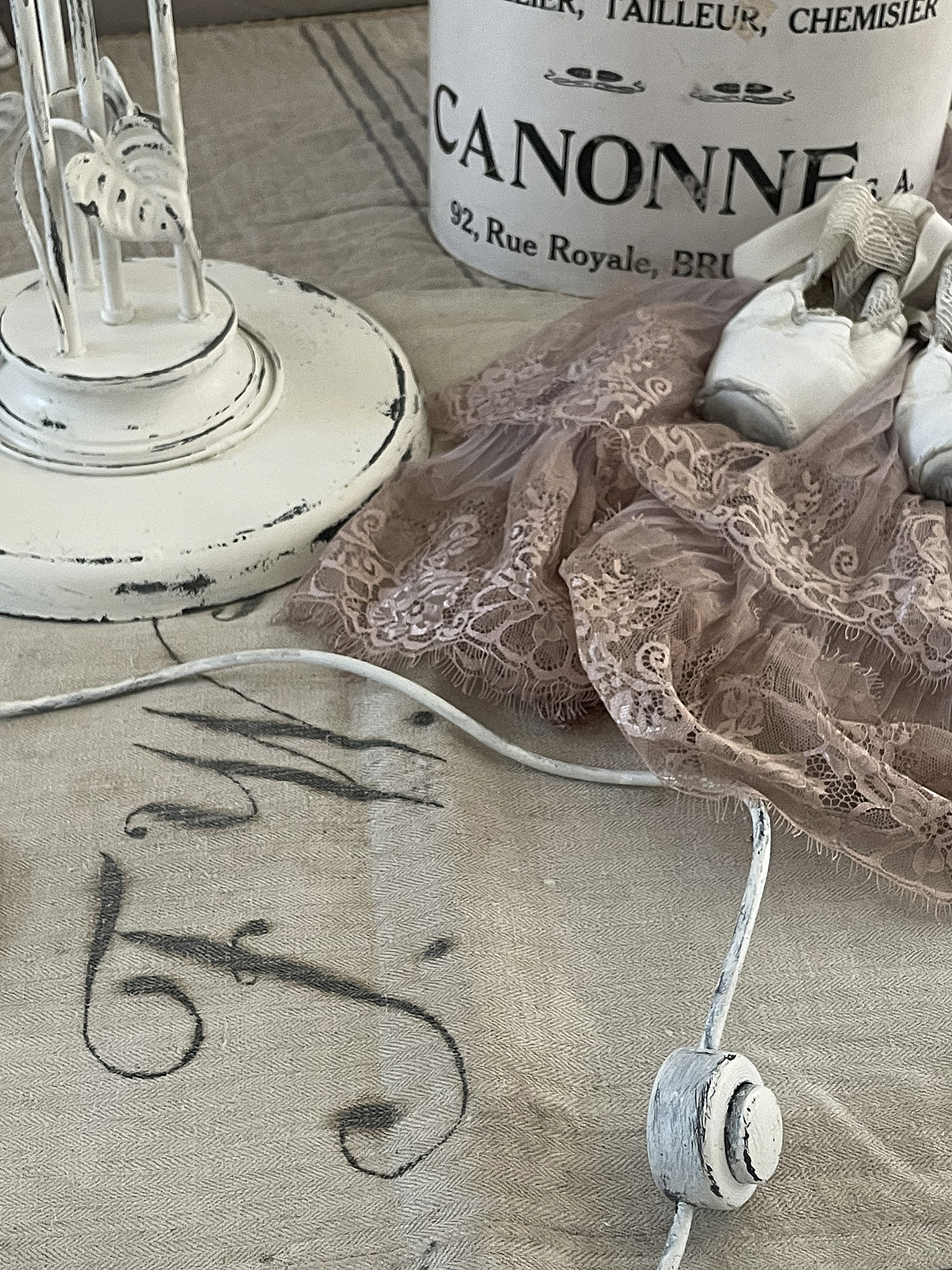 Vintage Dekoration mit Spitzenstoff und Ballettschuhen Stimmungsvolle Arrangement mit einem weißen Lampenstand, rosa Spitzenstoff und Ballettschuhen auf einem rustikalen Tisch